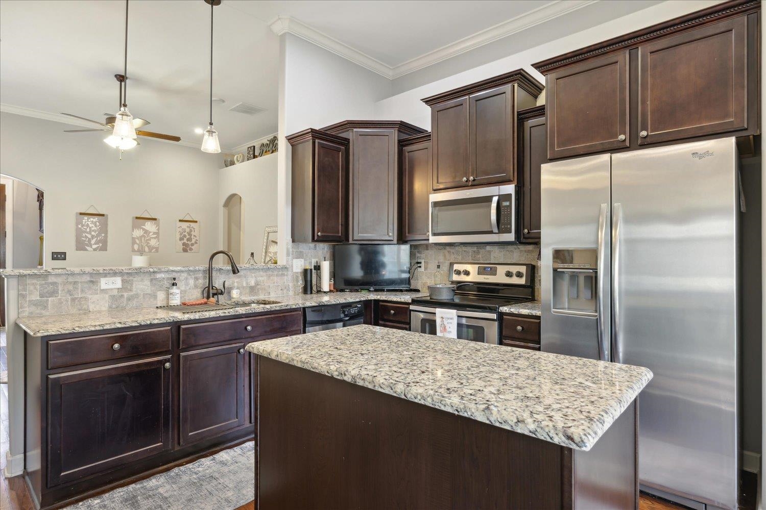 Kitchen with appliances with stainless steel finishes, tasteful backsplash, crown molding, ceiling fan, and sink