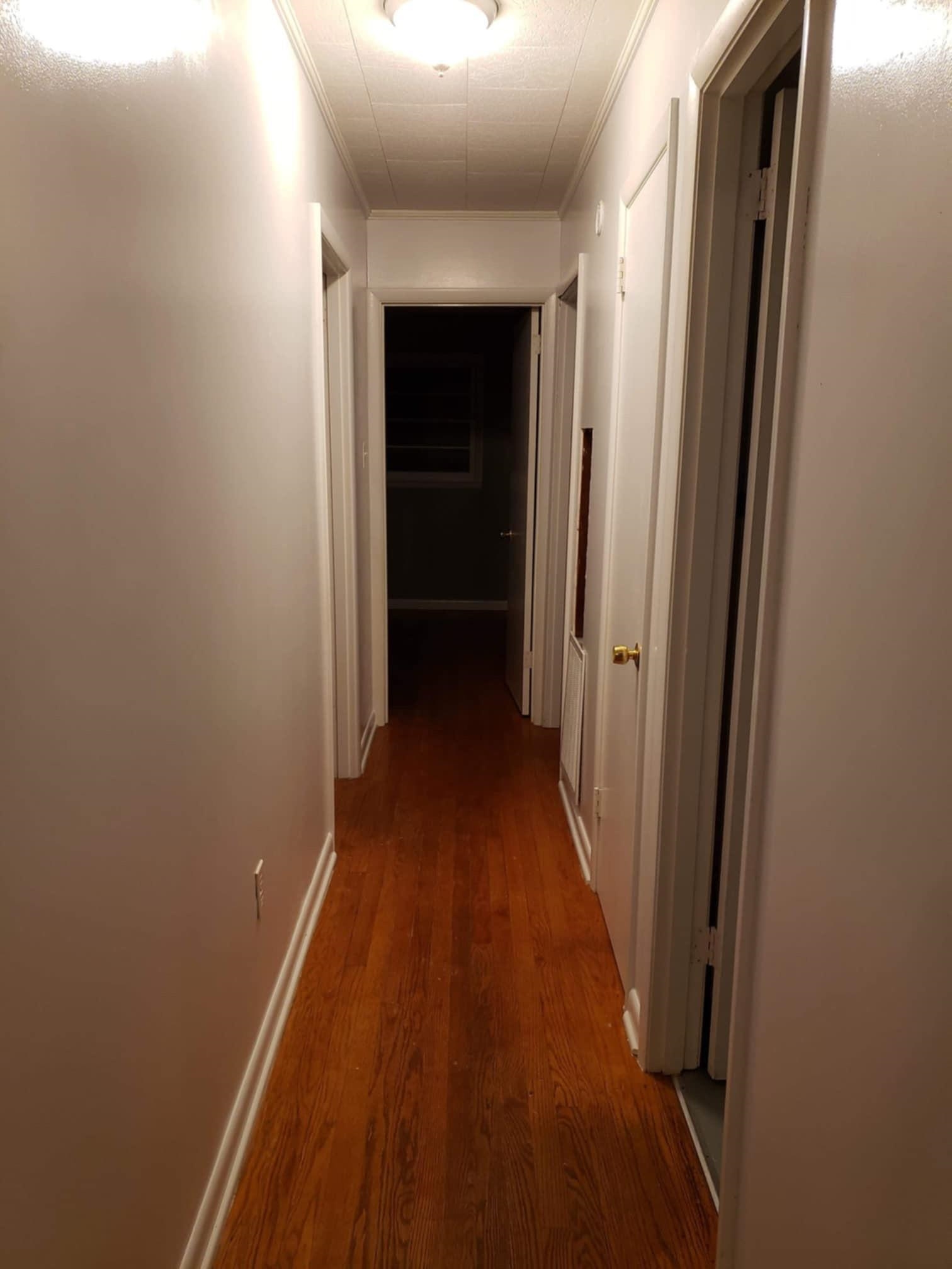 Hallway featuring dark wood-type flooring and crown molding