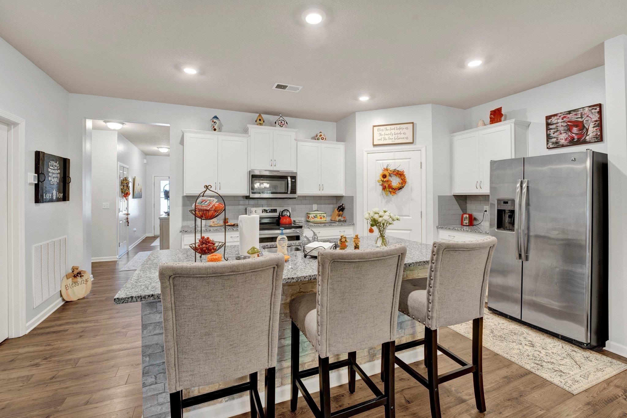 Kitchen with a kitchen island with sink, appliances with stainless steel finishes, dark wood-type flooring, and white cabinetry