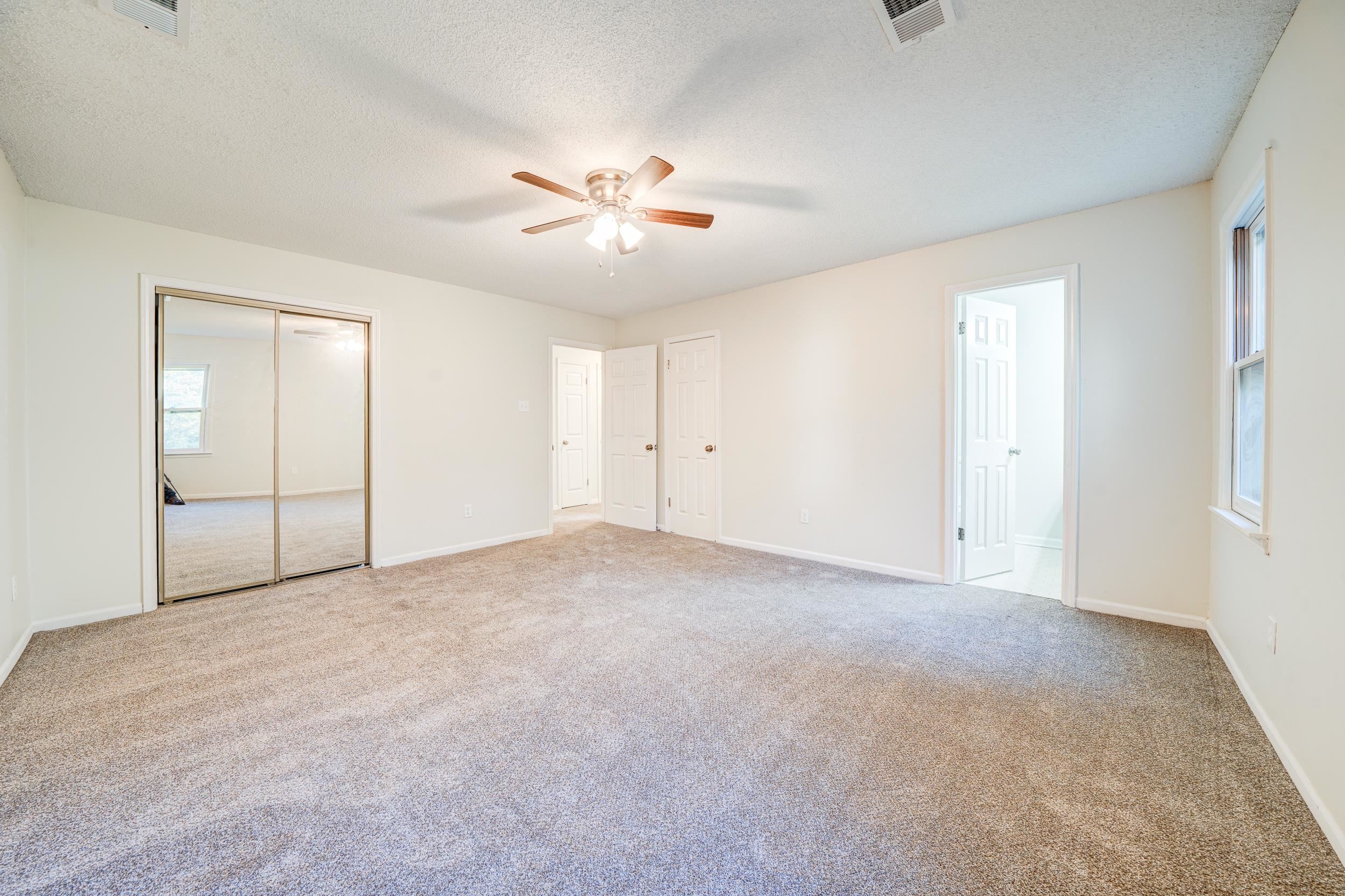 Unfurnished bedroom with ceiling fan, light colored carpet, and a textured ceiling