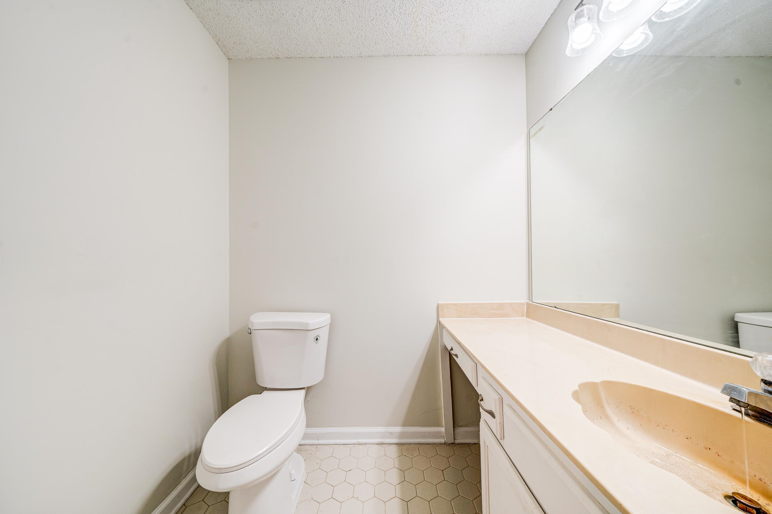 Bathroom with a textured ceiling, vanity, and toilet