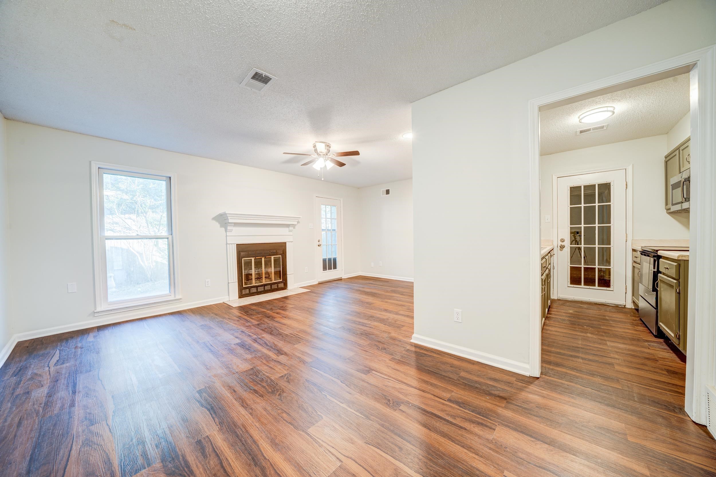 Unfurnished living room featuring ceiling fan, a textured ceiling, and dark wood-type flooring