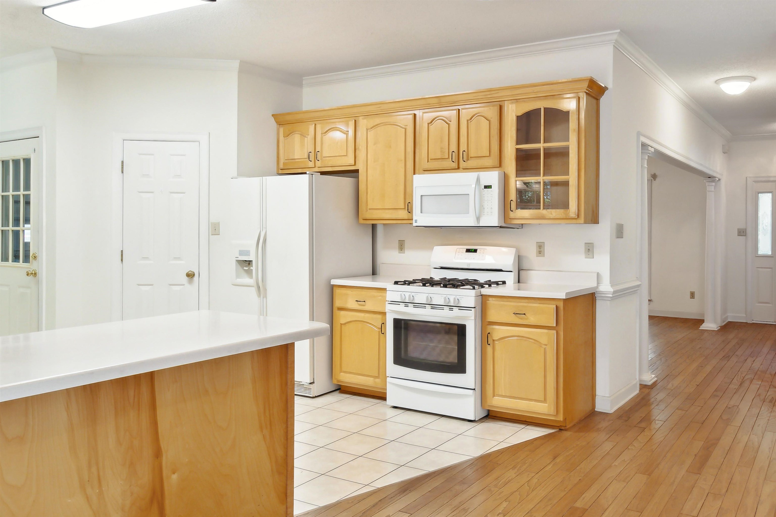 Kitchen featuring white appliances, ornamental molding, light brown cabinets, and light hardwood / wood-style flooring
