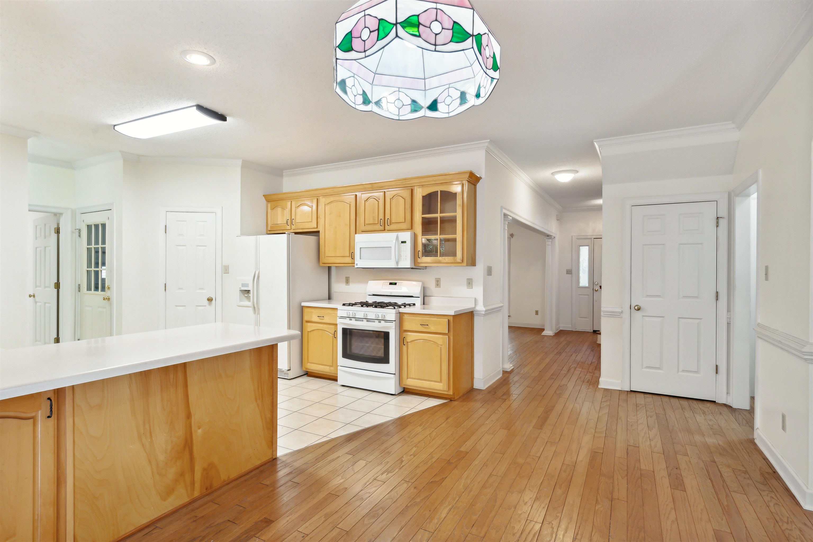 Kitchen with crown molding, light hardwood / wood-style floors, and white appliances