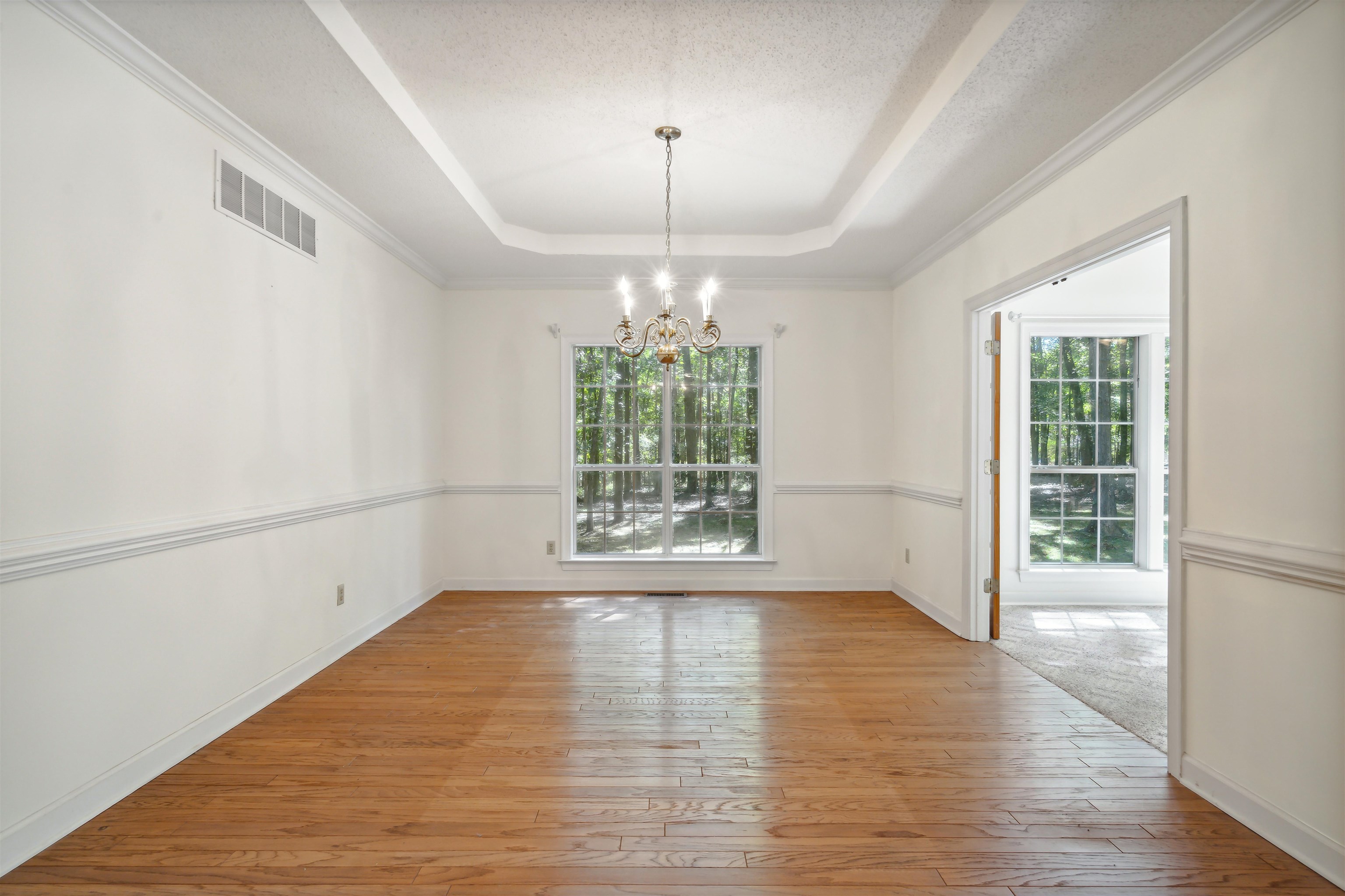 Unfurnished dining area with ornamental molding, light wood-type flooring, and a textured ceiling