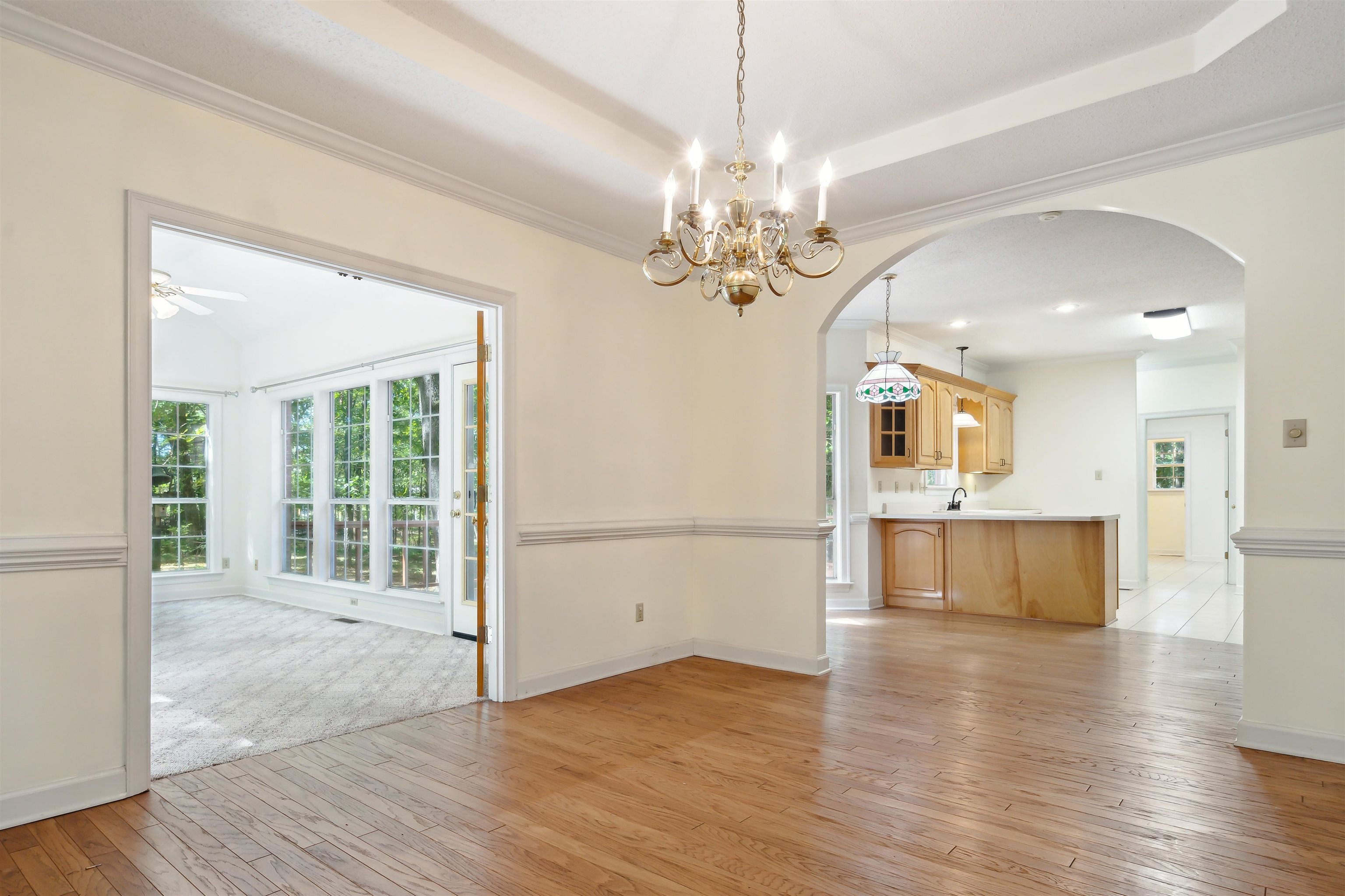 Unfurnished dining area featuring ceiling fan with notable chandelier, light wood-type flooring, and crown molding