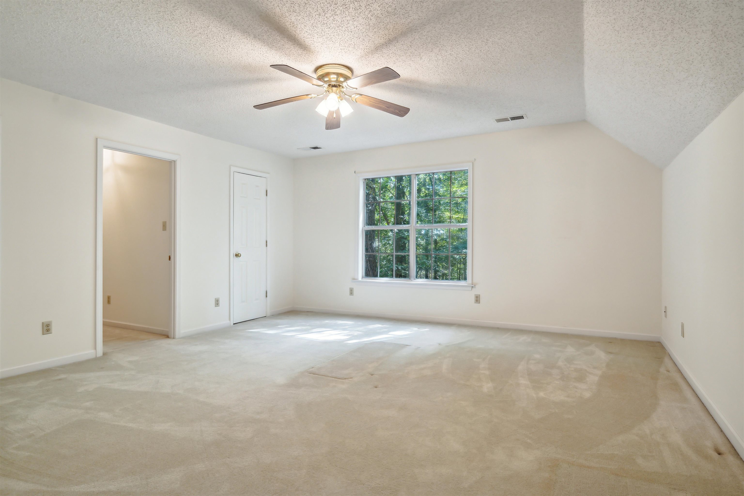 Unfurnished bedroom with ceiling fan, light colored carpet, a textured ceiling, and lofted ceiling