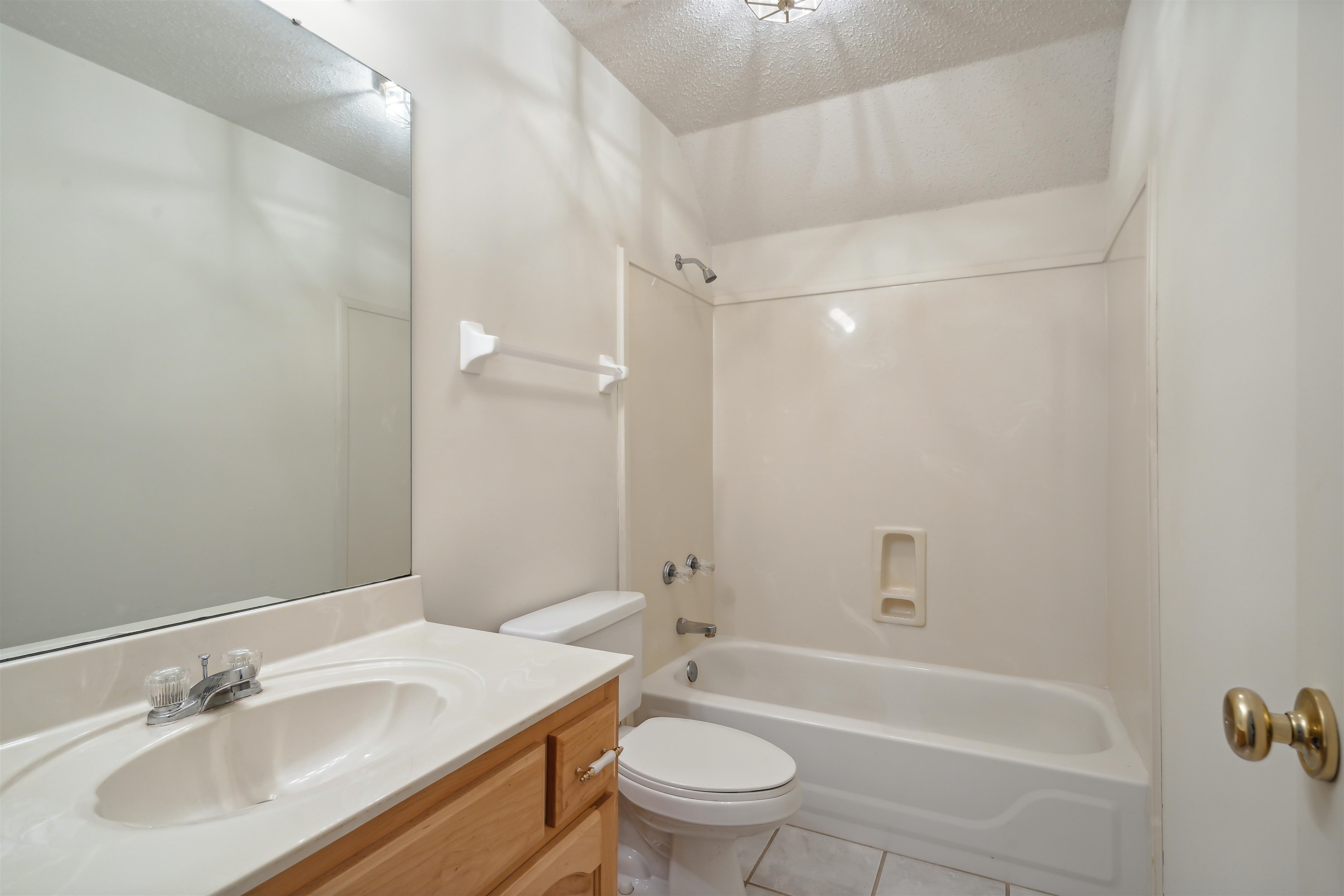 Full bathroom featuring a textured ceiling, tile patterned floors, shower / bathing tub combination, vanity, and toilet