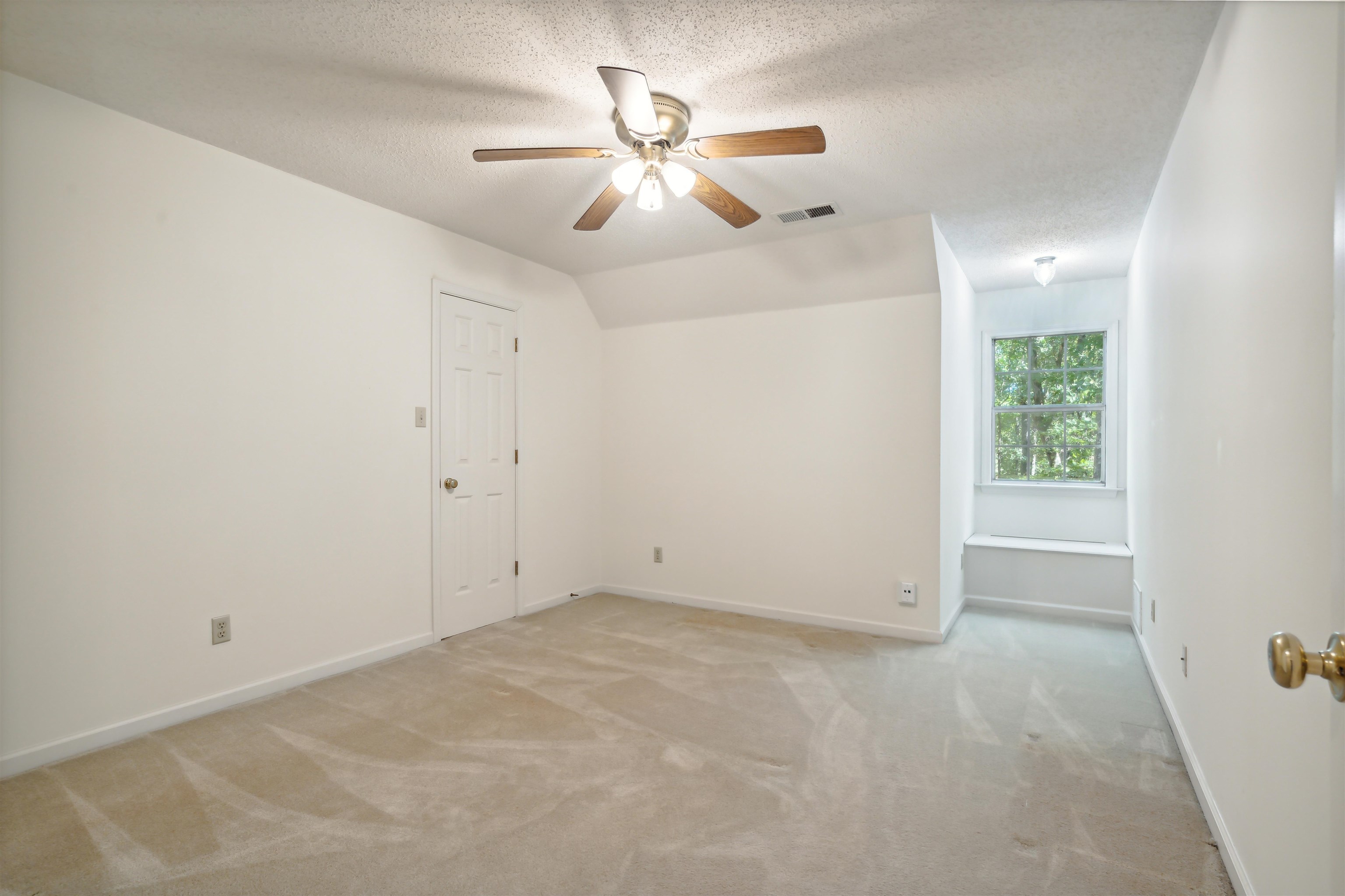 Carpeted empty room featuring ceiling fan, a textured ceiling, and lofted ceiling