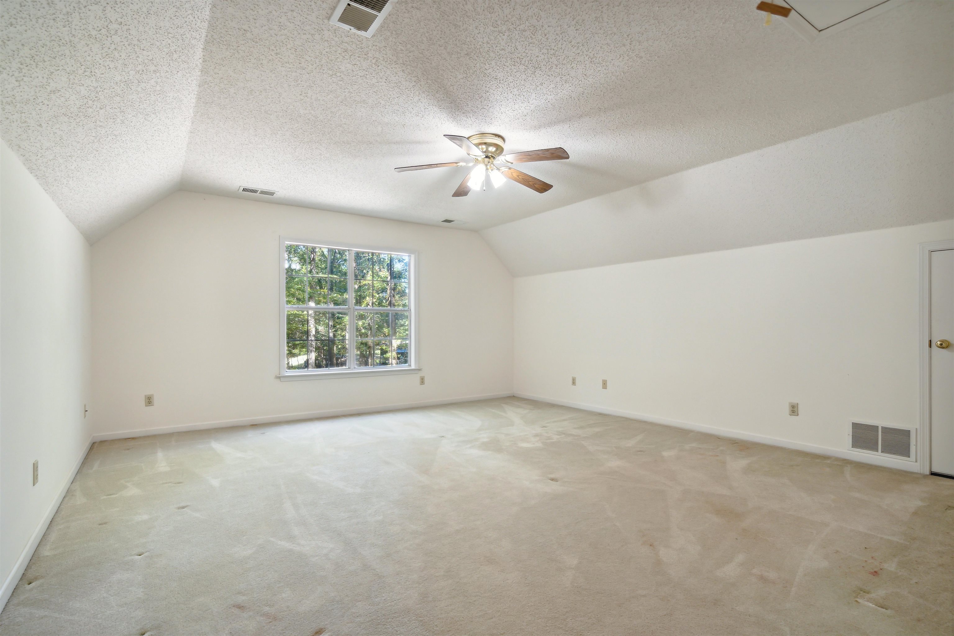Bonus room with ceiling fan, light colored carpet, a textured ceiling, and lofted ceiling