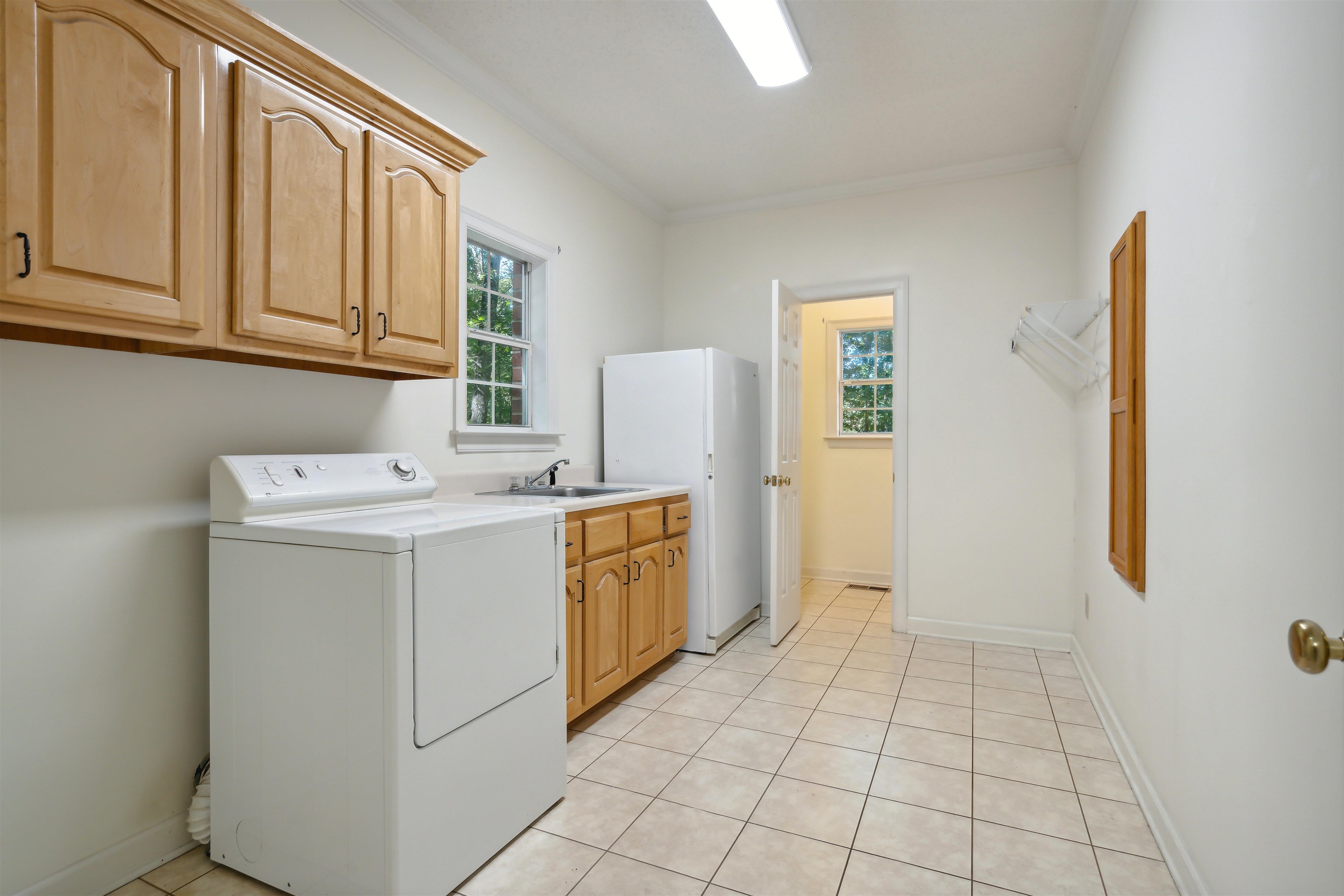 Clothes washing area with cabinets, ornamental molding, and a healthy amount of sunlight