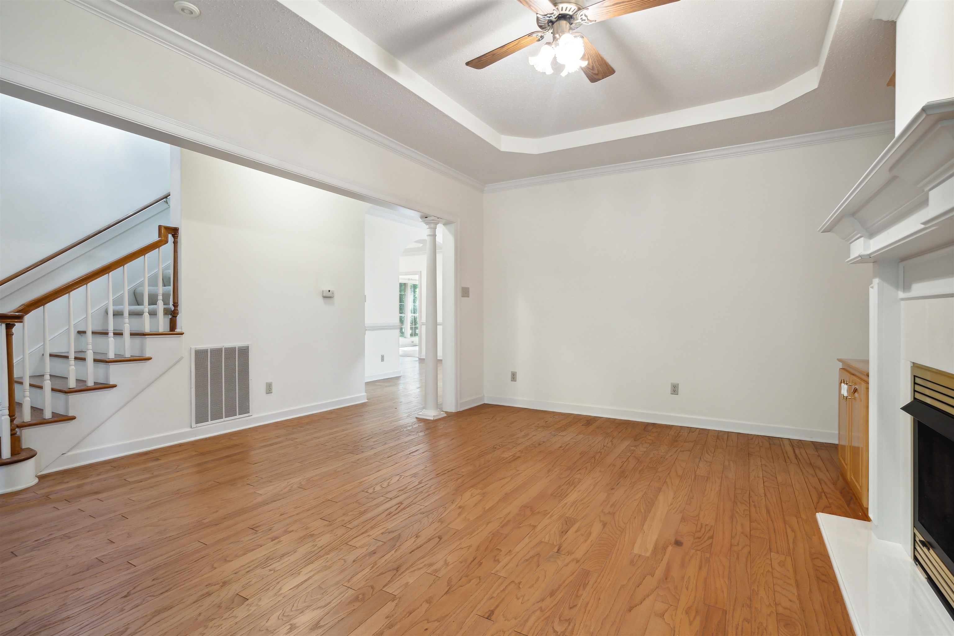 Unfurnished living room with crown molding, a tray ceiling, and light hardwood / wood-style flooring