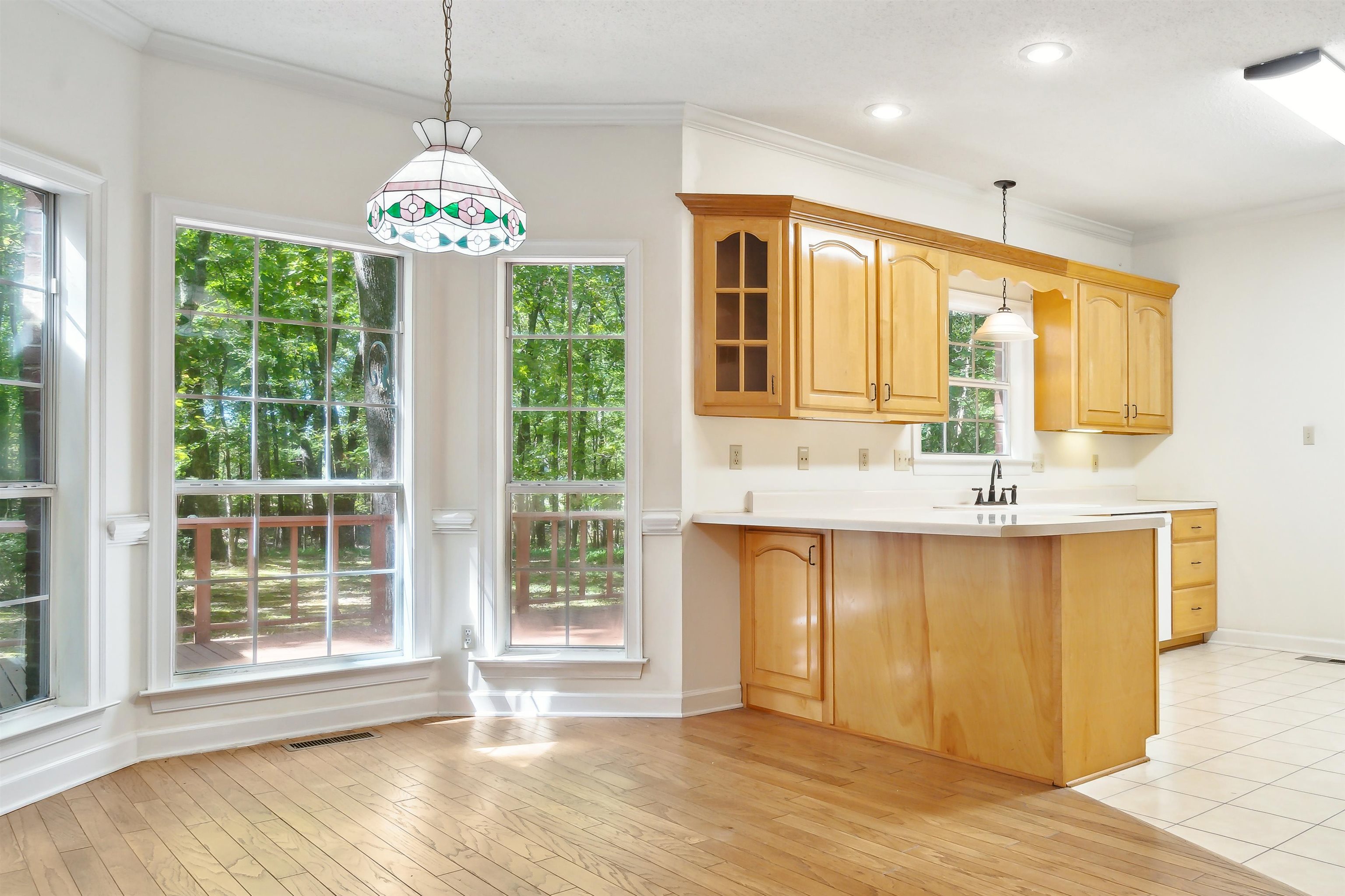 Kitchen featuring light wood-type flooring, kitchen peninsula, hanging light fixtures, and a healthy amount of sunlight