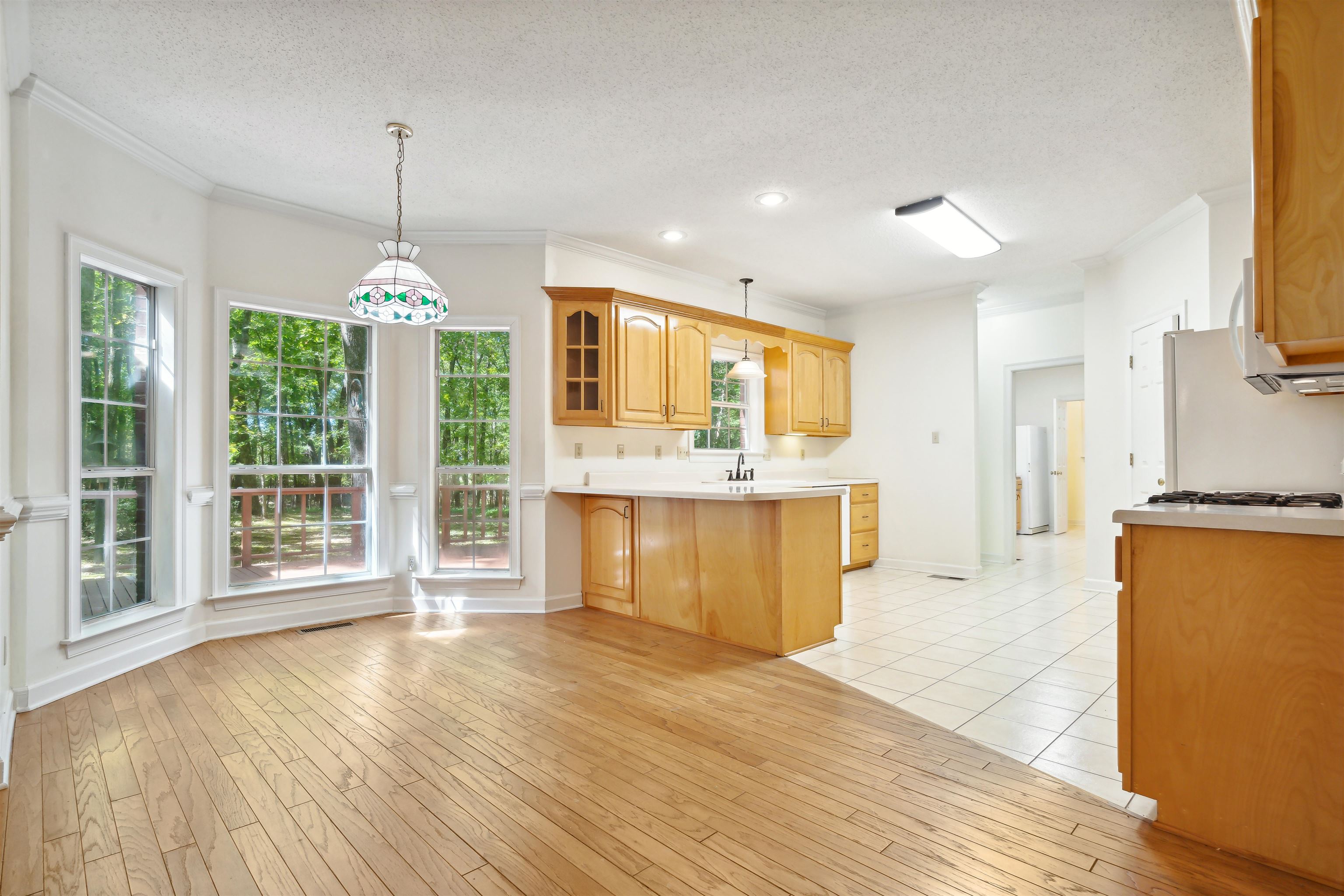 Kitchen featuring light wood-type flooring, a textured ceiling, decorative light fixtures, and plenty of natural light
