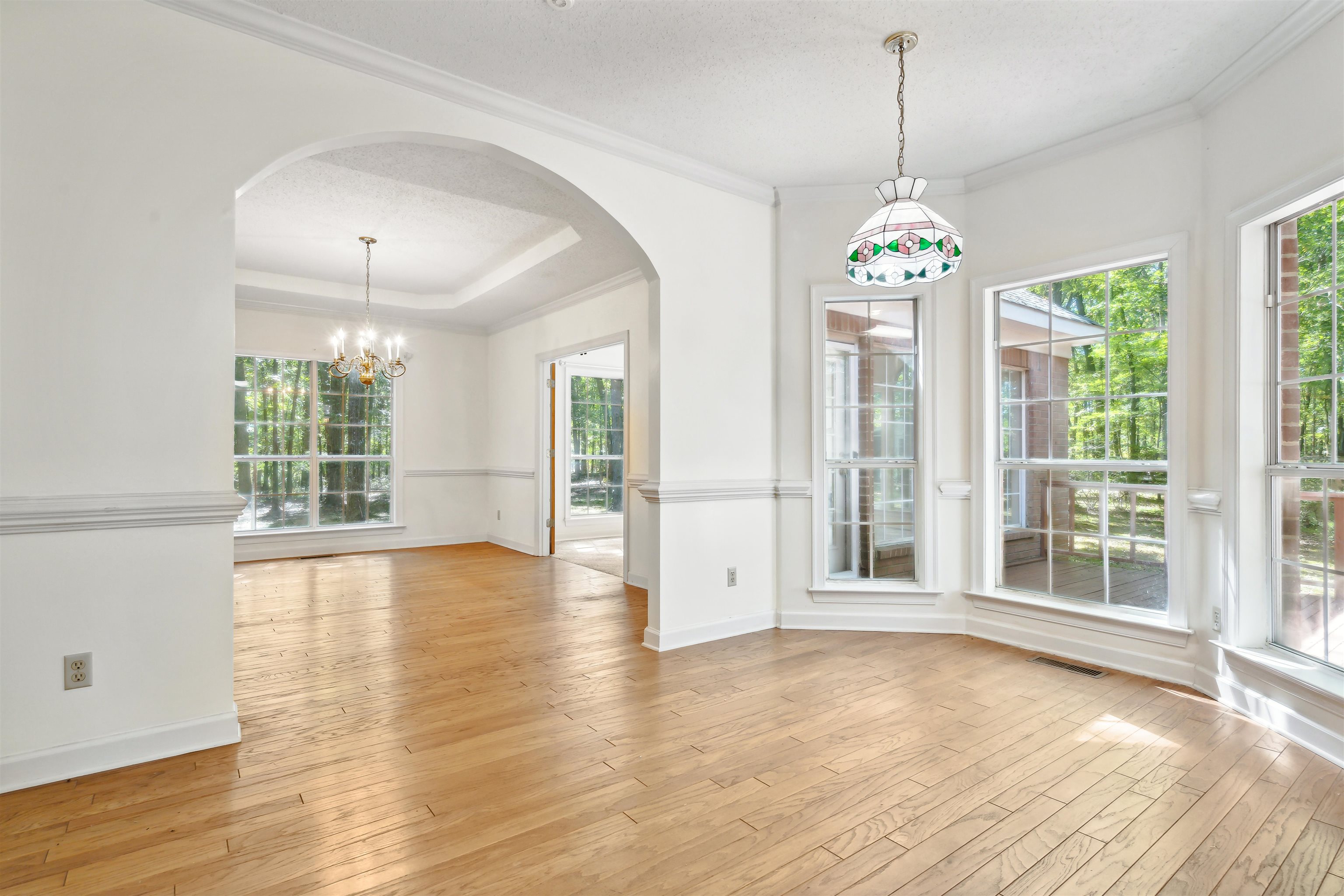 Unfurnished dining area featuring ornamental molding, light wood-type flooring, a textured ceiling, and a notable chandelier