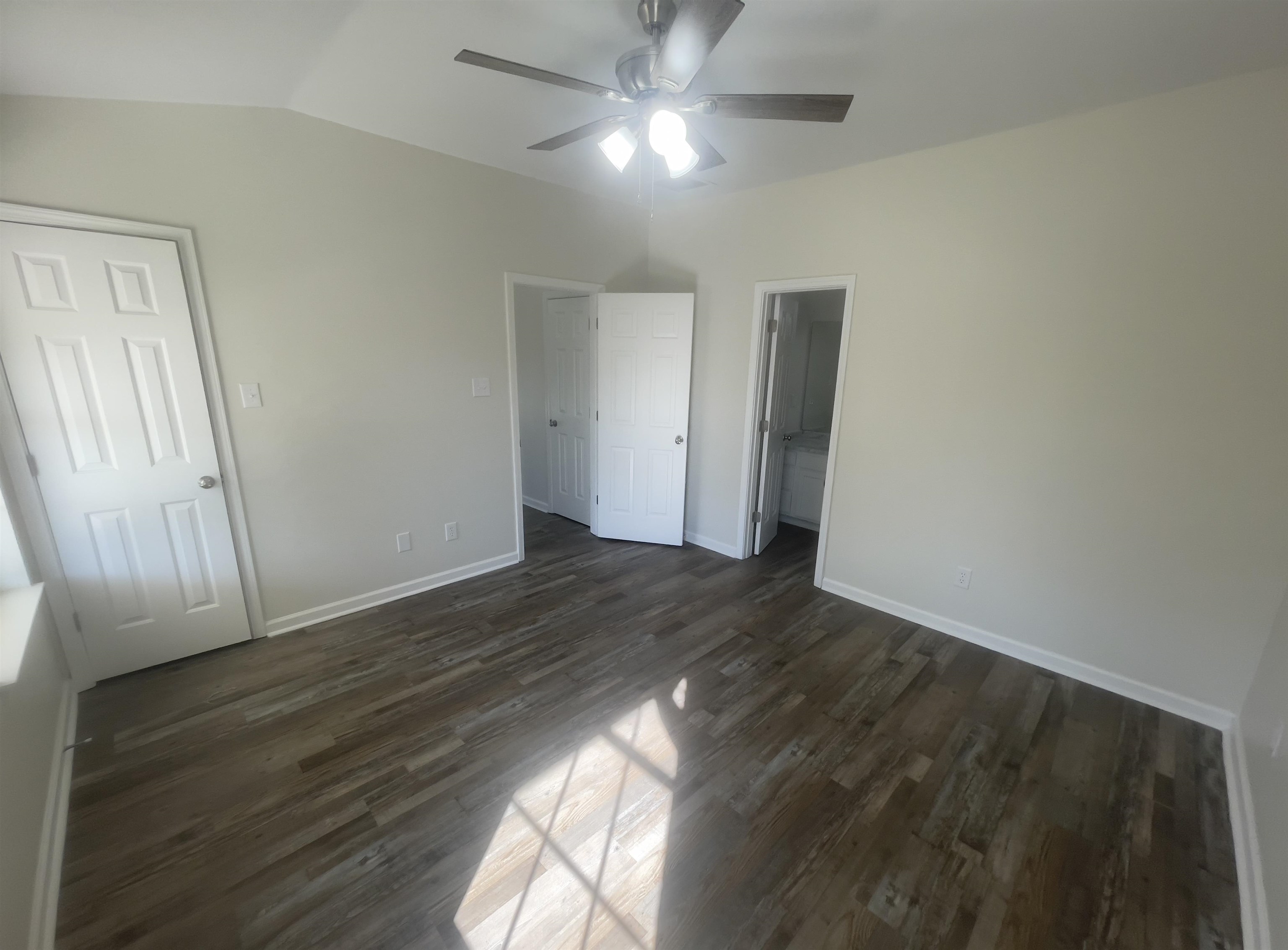 Unfurnished bedroom with a closet, lofted ceiling, ceiling fan, and dark wood-type flooring