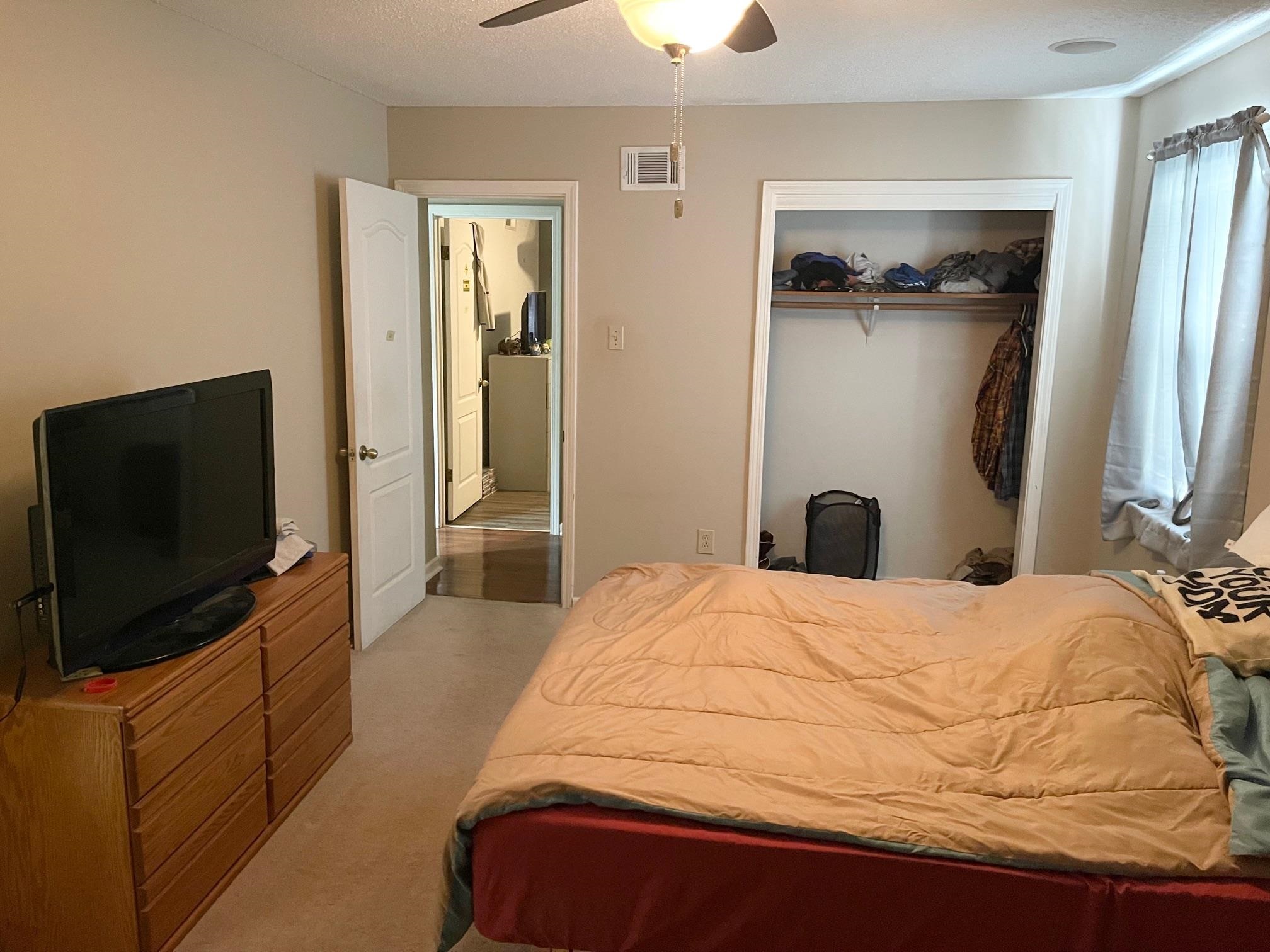 Carpeted bedroom with ceiling fan, a textured ceiling, and a closet