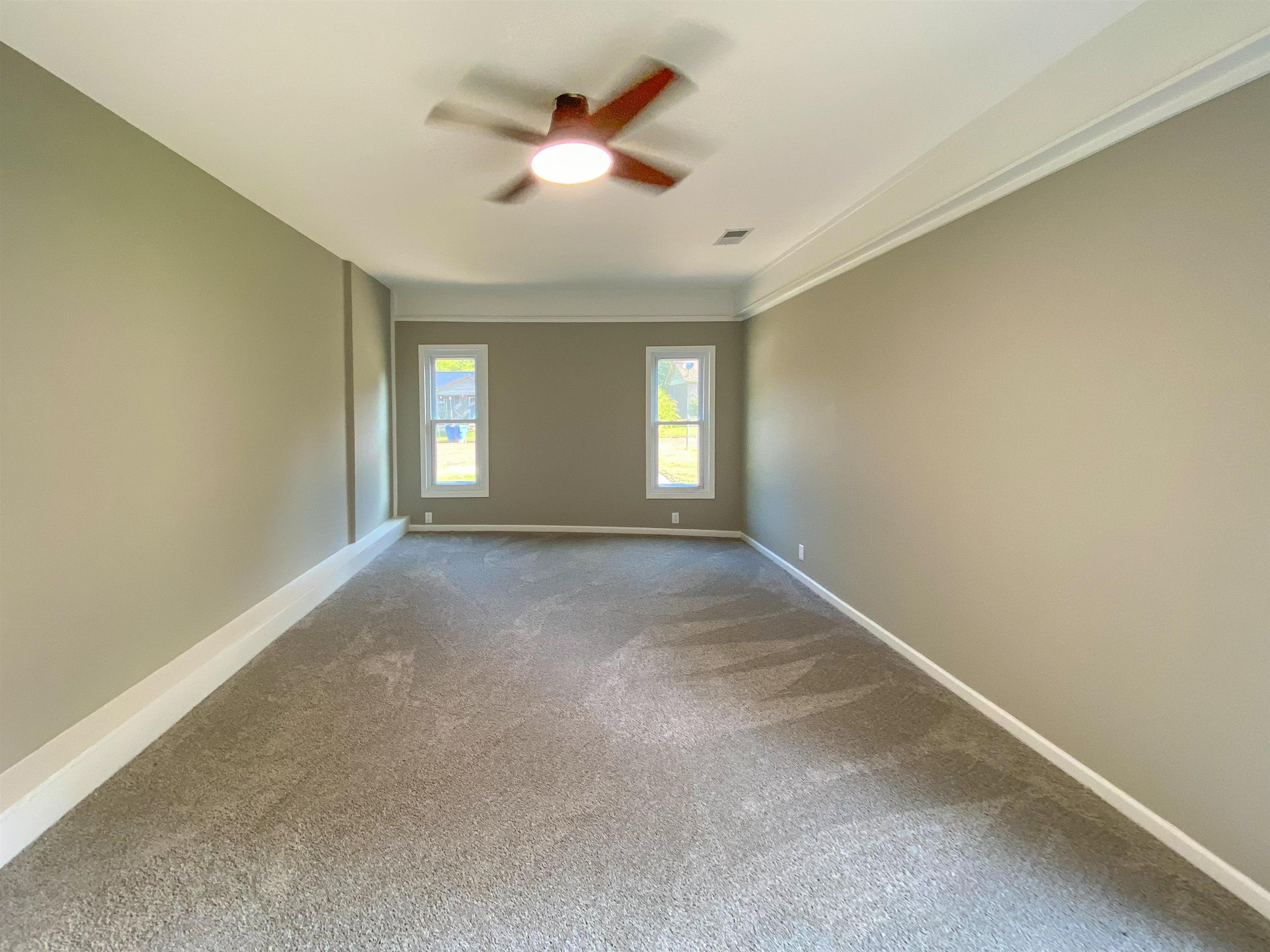 Carpeted empty room featuring crown molding and ceiling fan