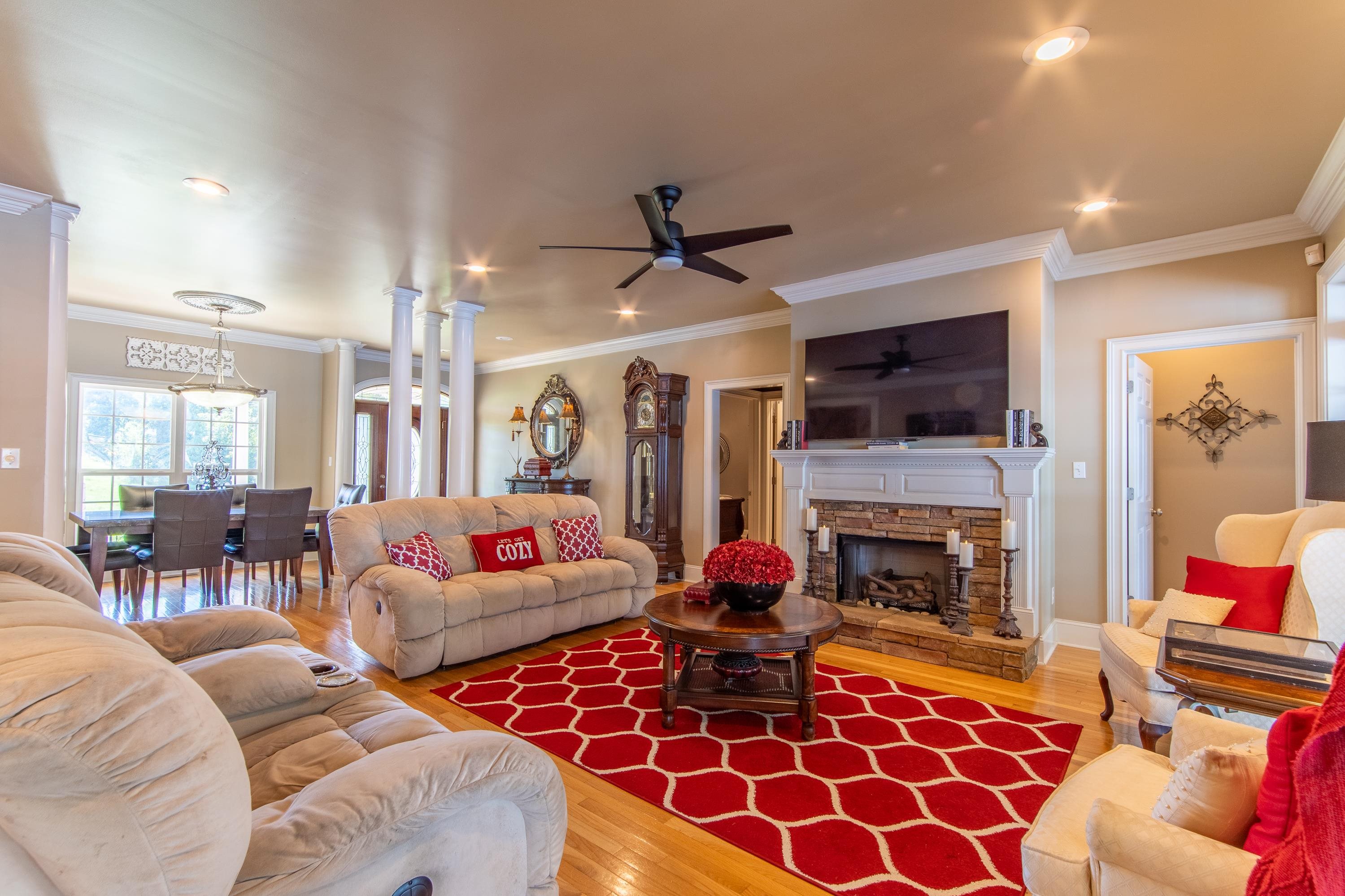 Living room with a fireplace, crown molding, hardwood / wood-style floors, and ceiling fan