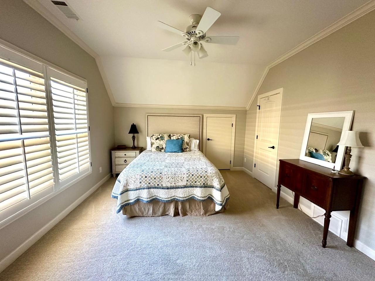 Carpeted bedroom with lofted ceiling, crown molding, multiple windows, and ceiling fan