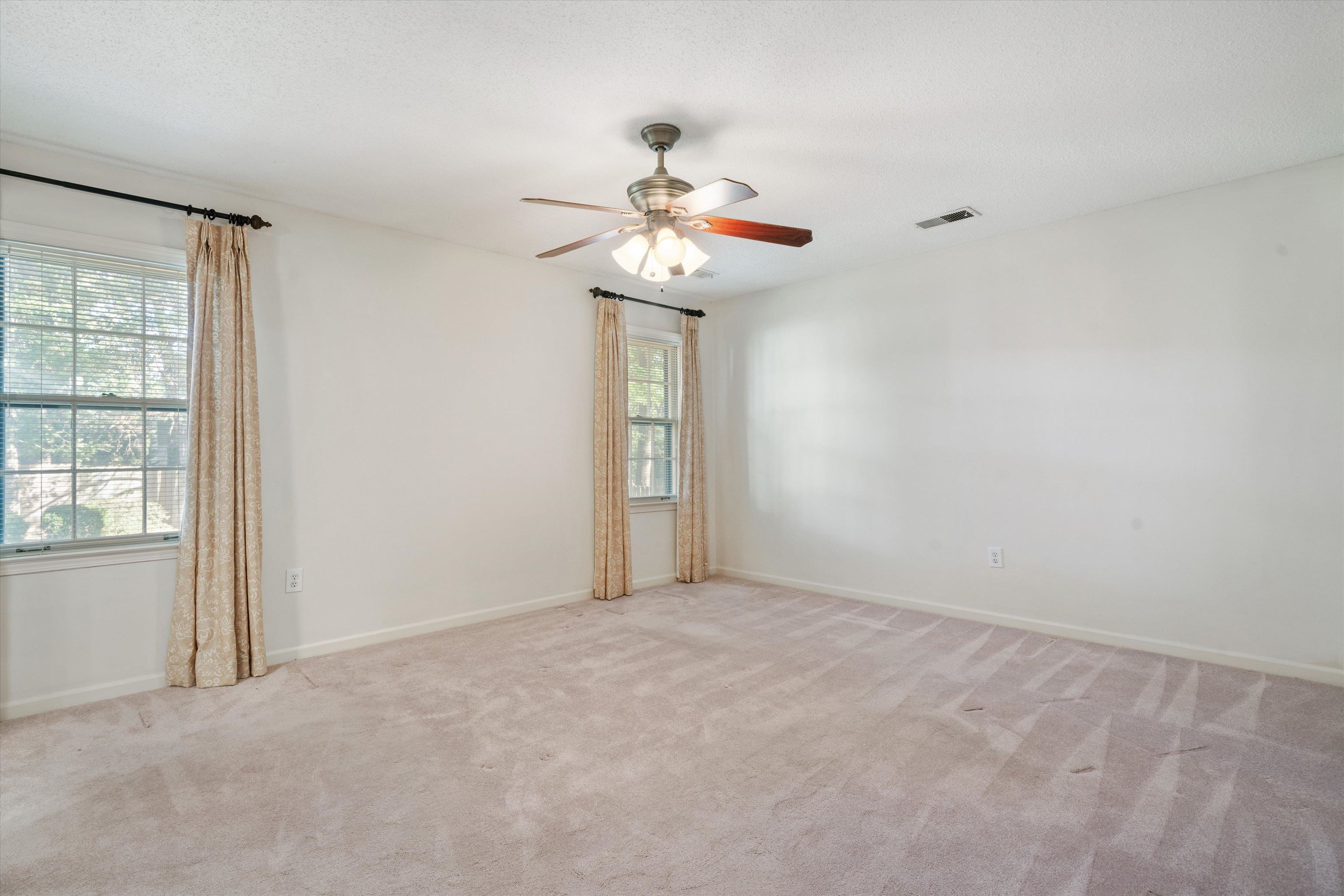 Carpeted empty room with ceiling fan and a wealth of natural light