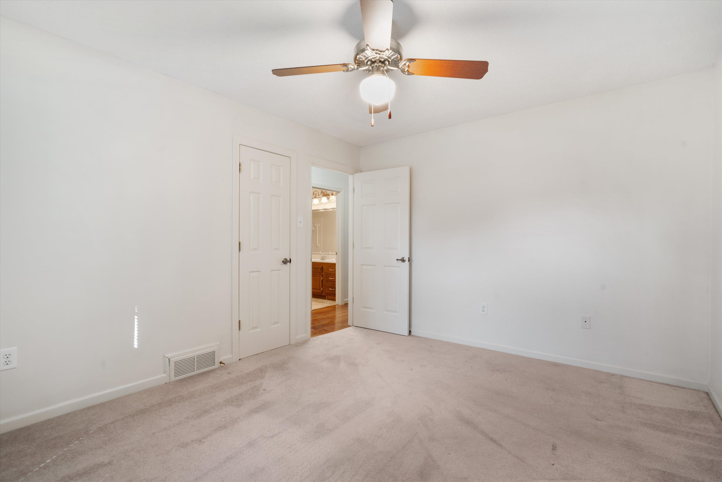 Empty room featuring ceiling fan and light carpet