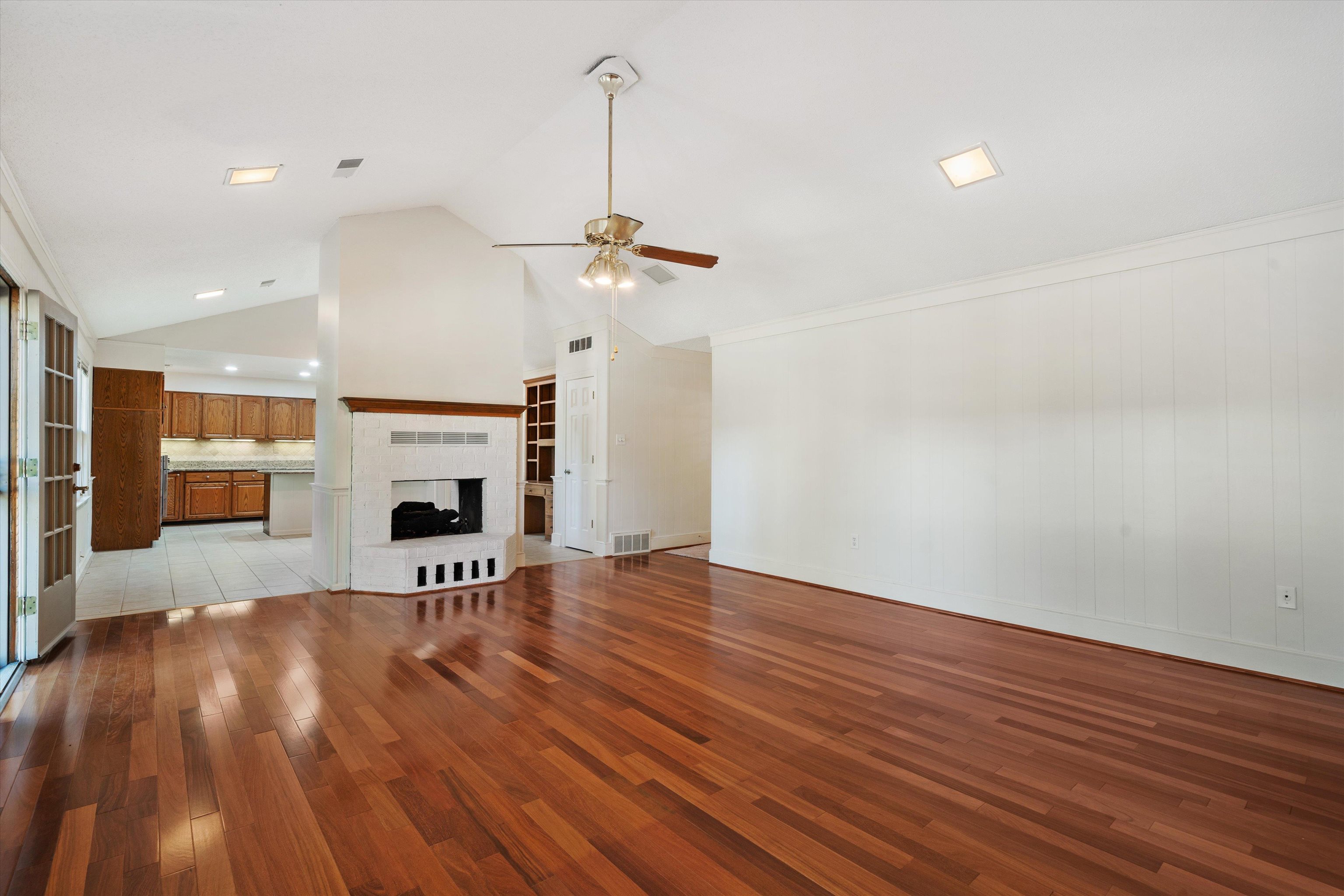 Unfurnished living room featuring ceiling fan, lofted ceiling, ornamental molding, light hardwood / wood-style flooring, and a tiled fireplace