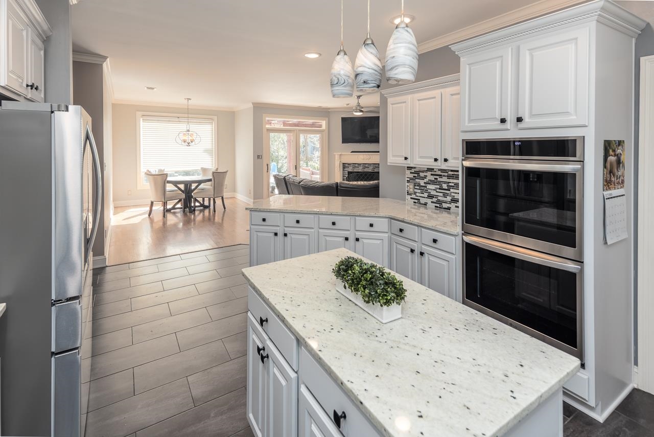 Kitchen featuring decorative light fixtures, white cabinetry, stainless steel appliances, dark hardwood / wood-style floors, and a center island