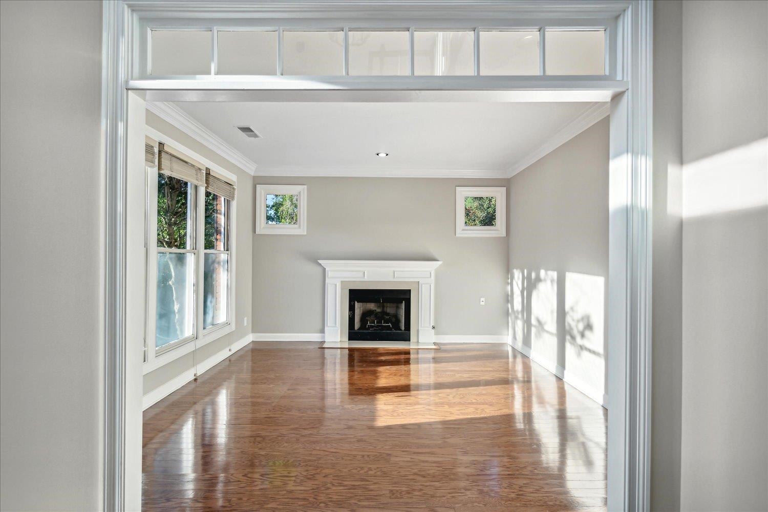 Unfurnished living room featuring ornamental molding and dark wood-type flooring