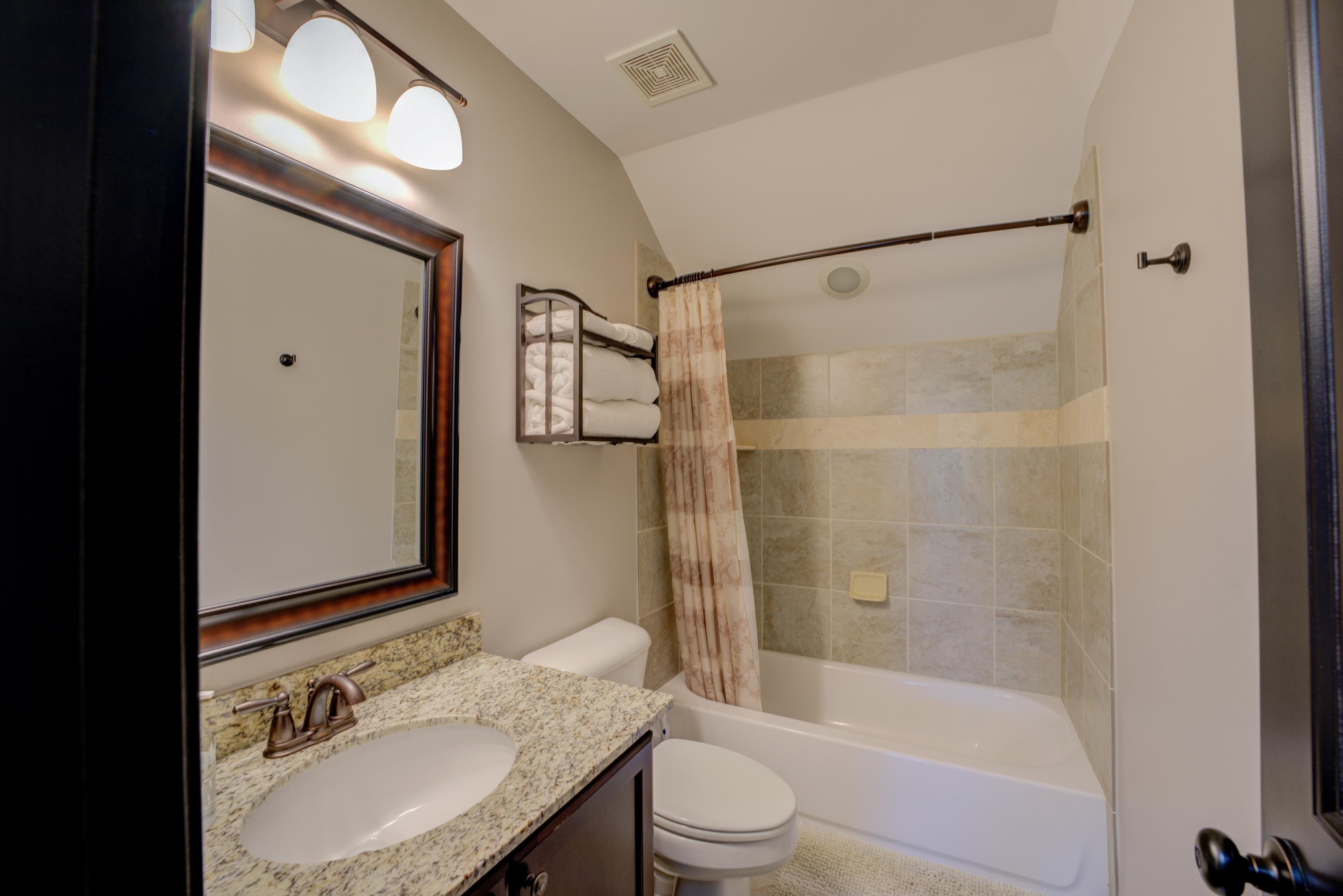 Full bathroom featuring shower / bath combination with curtain, lofted ceiling, vanity, and toilet