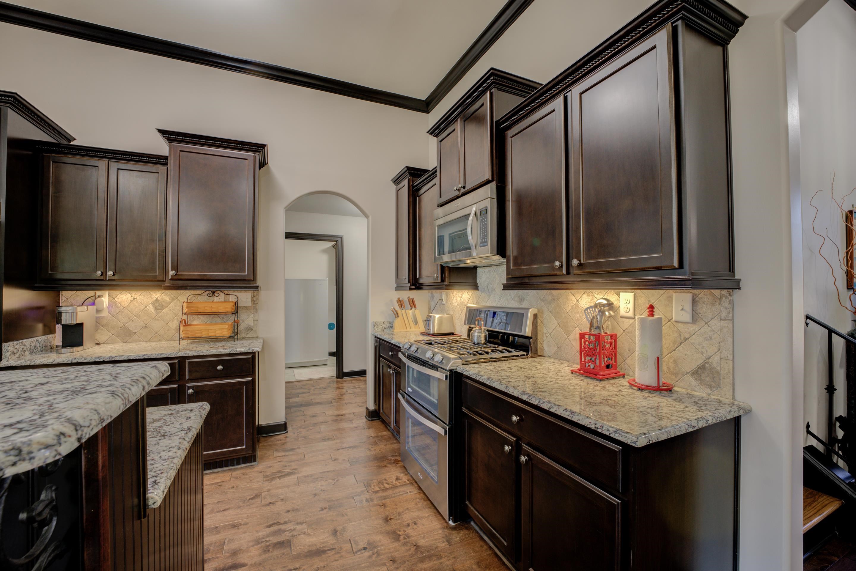 Kitchen featuring crown molding, appliances with stainless steel finishes, light hardwood / wood-style flooring, and dark brown cabinetry