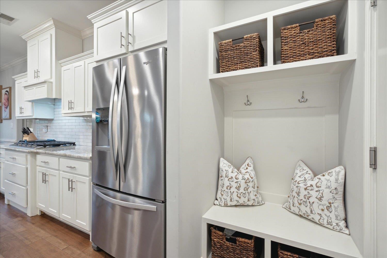 Kitchen featuring stainless steel appliances, white cabinets, dark hardwood / wood-style flooring, ornamental molding, and backsplash