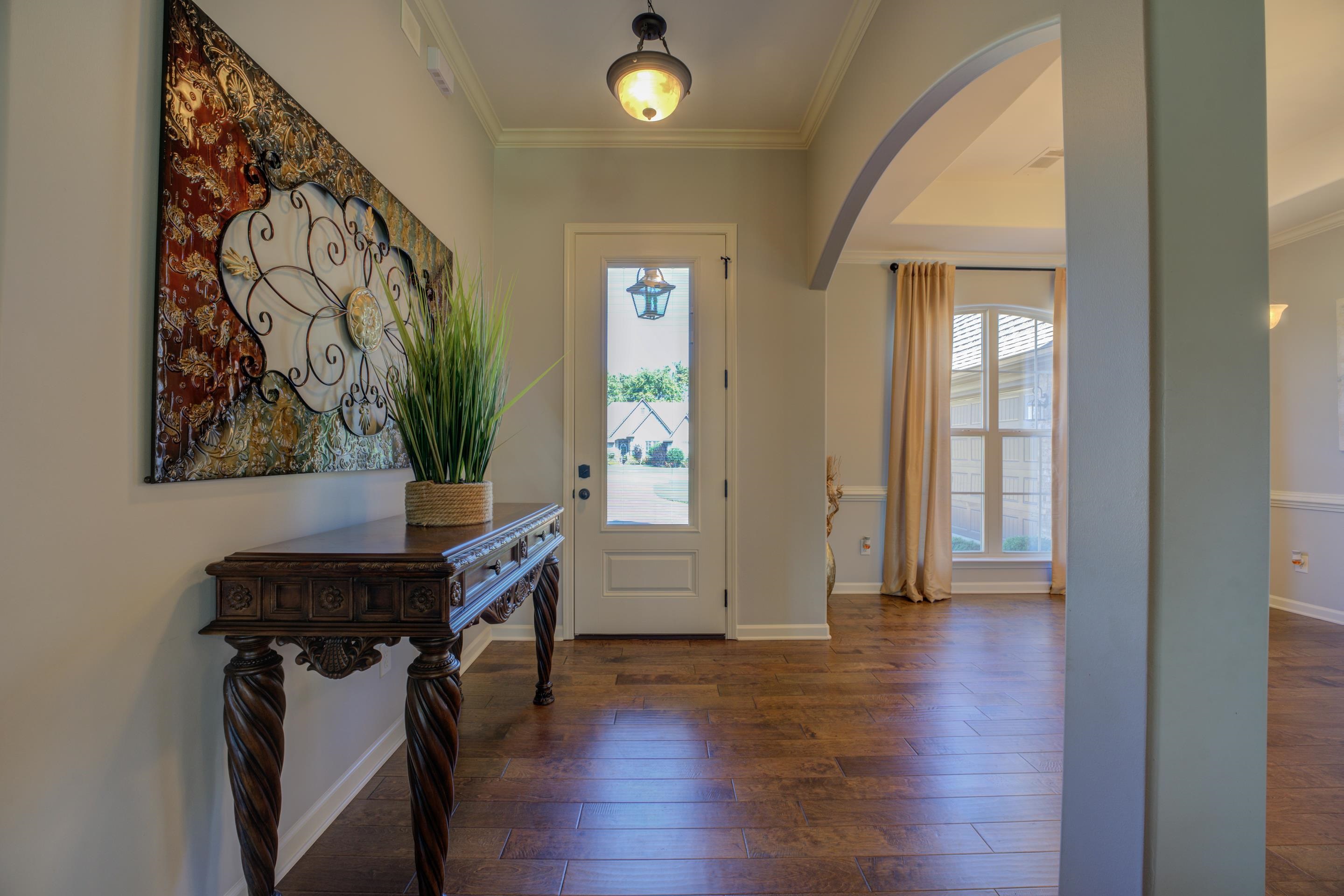 Entryway with dark wood-type flooring, ornamental molding, and a healthy amount of sunlight