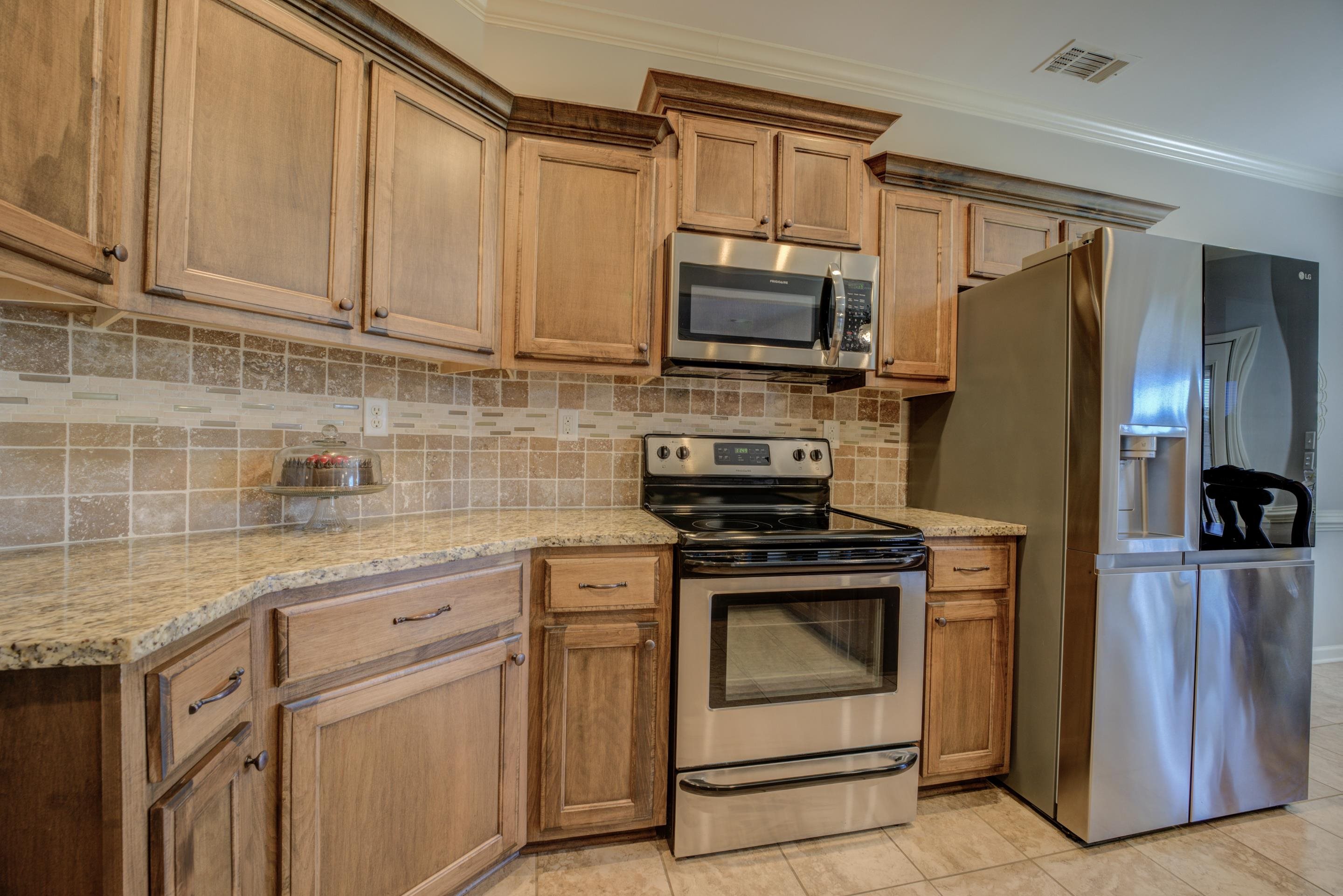 Kitchen featuring light stone counters, stainless steel appliances, crown molding, and light tile patterned floors