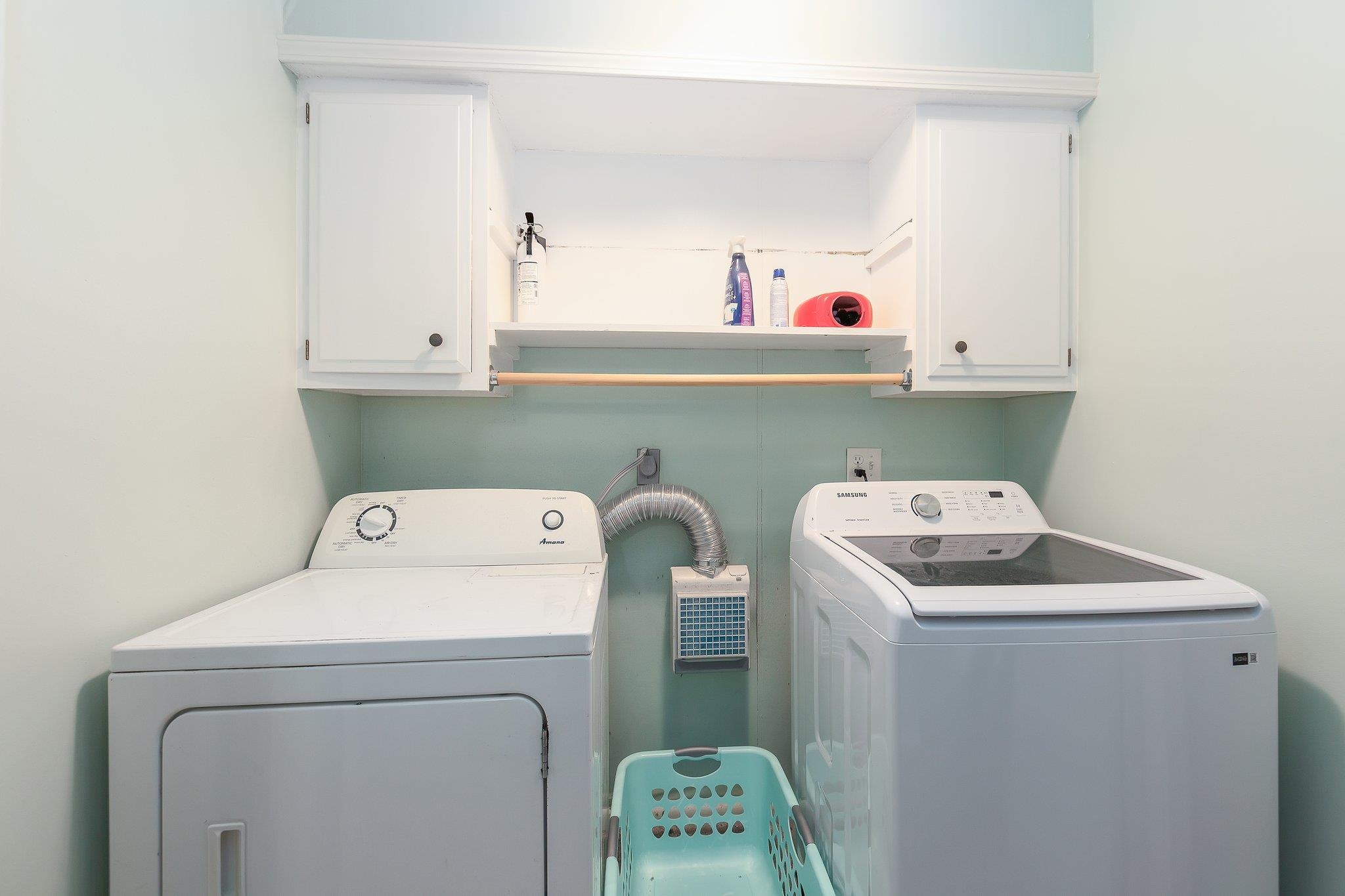 Laundry room with separate washer and dryer and cabinets