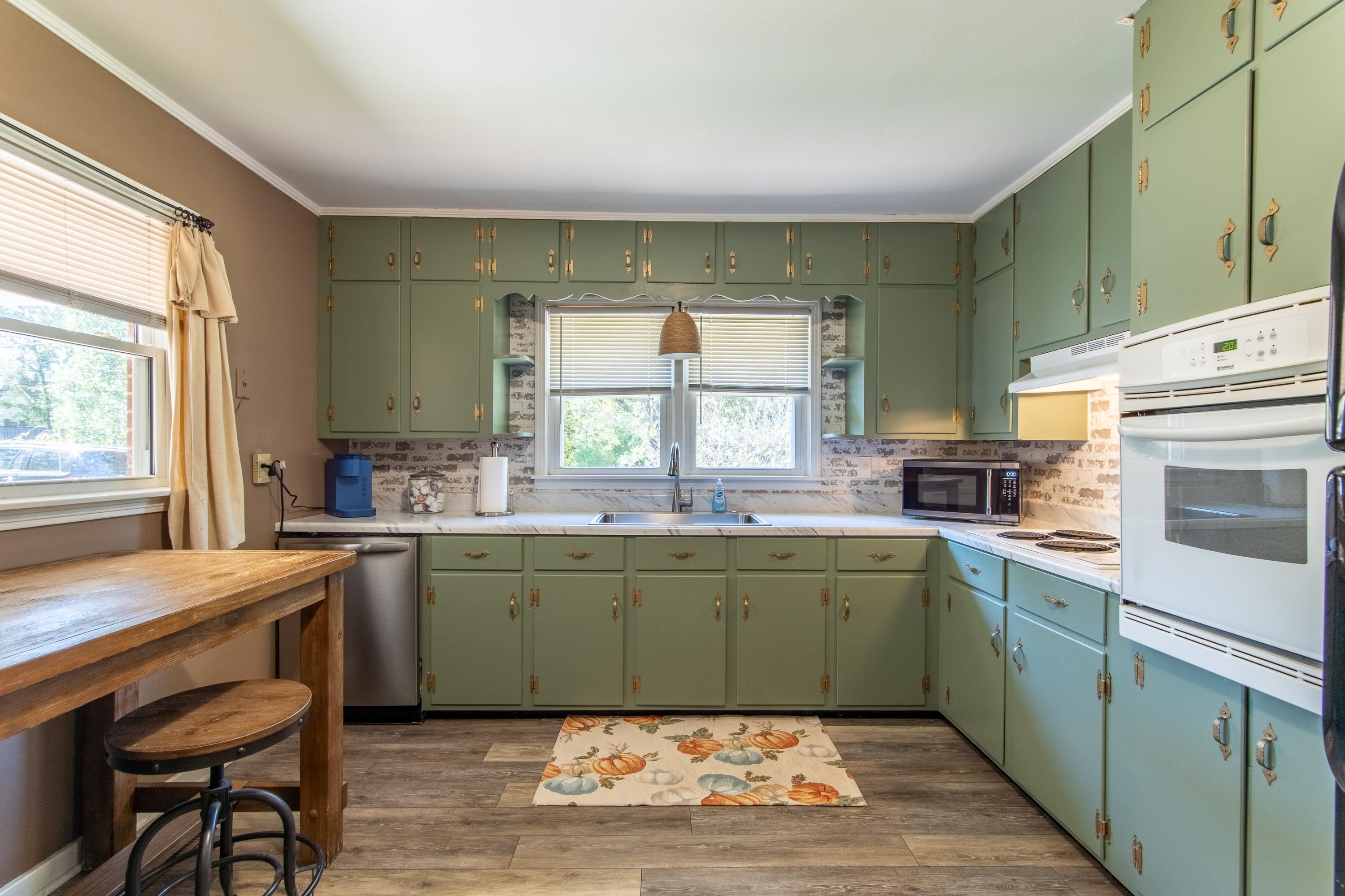 Kitchen featuring appliances with stainless steel finishes, dark hardwood / wood-style floors, sink, and green cabinets