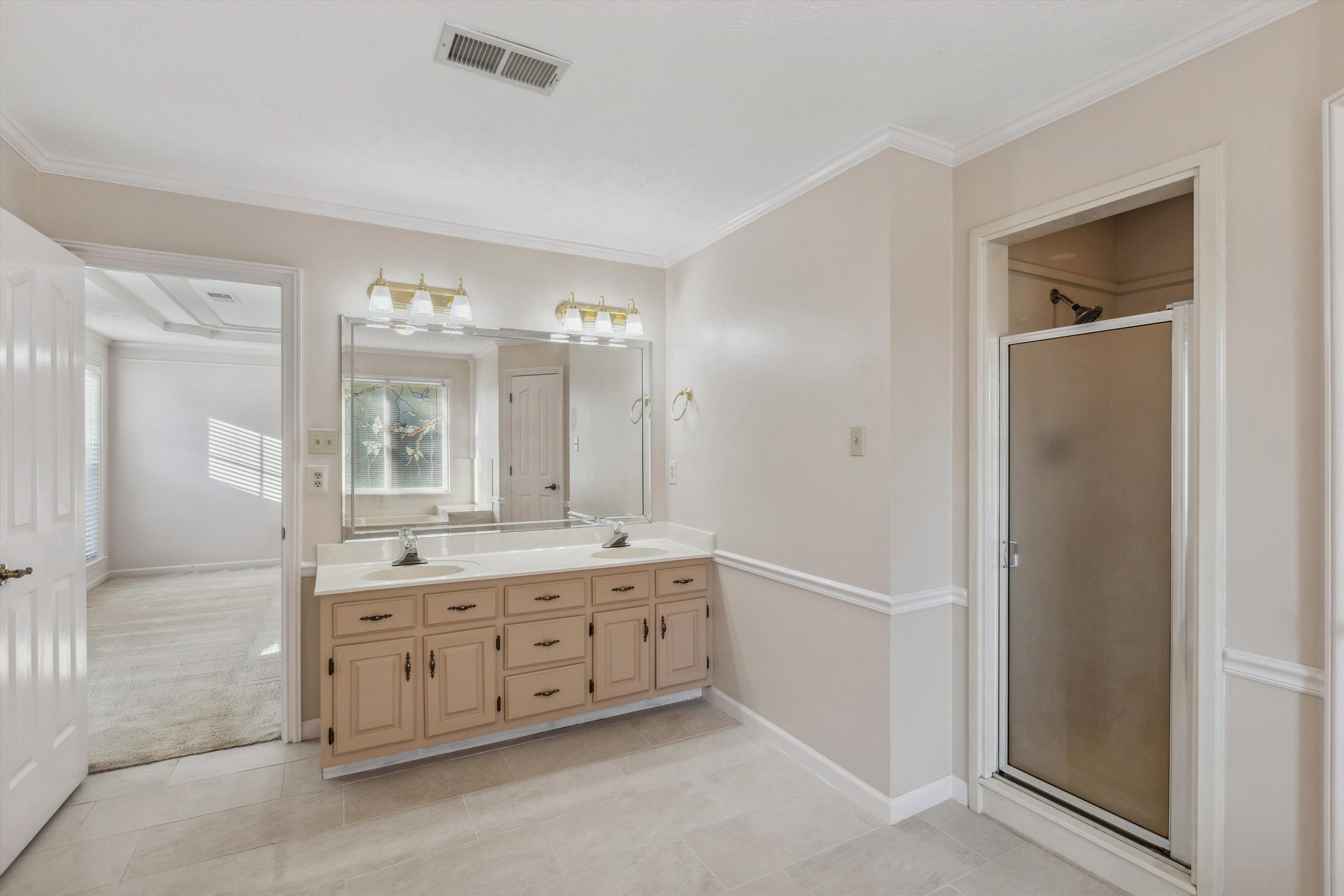 Bathroom featuring vanity, a shower with shower door, crown molding, and tile patterned floors