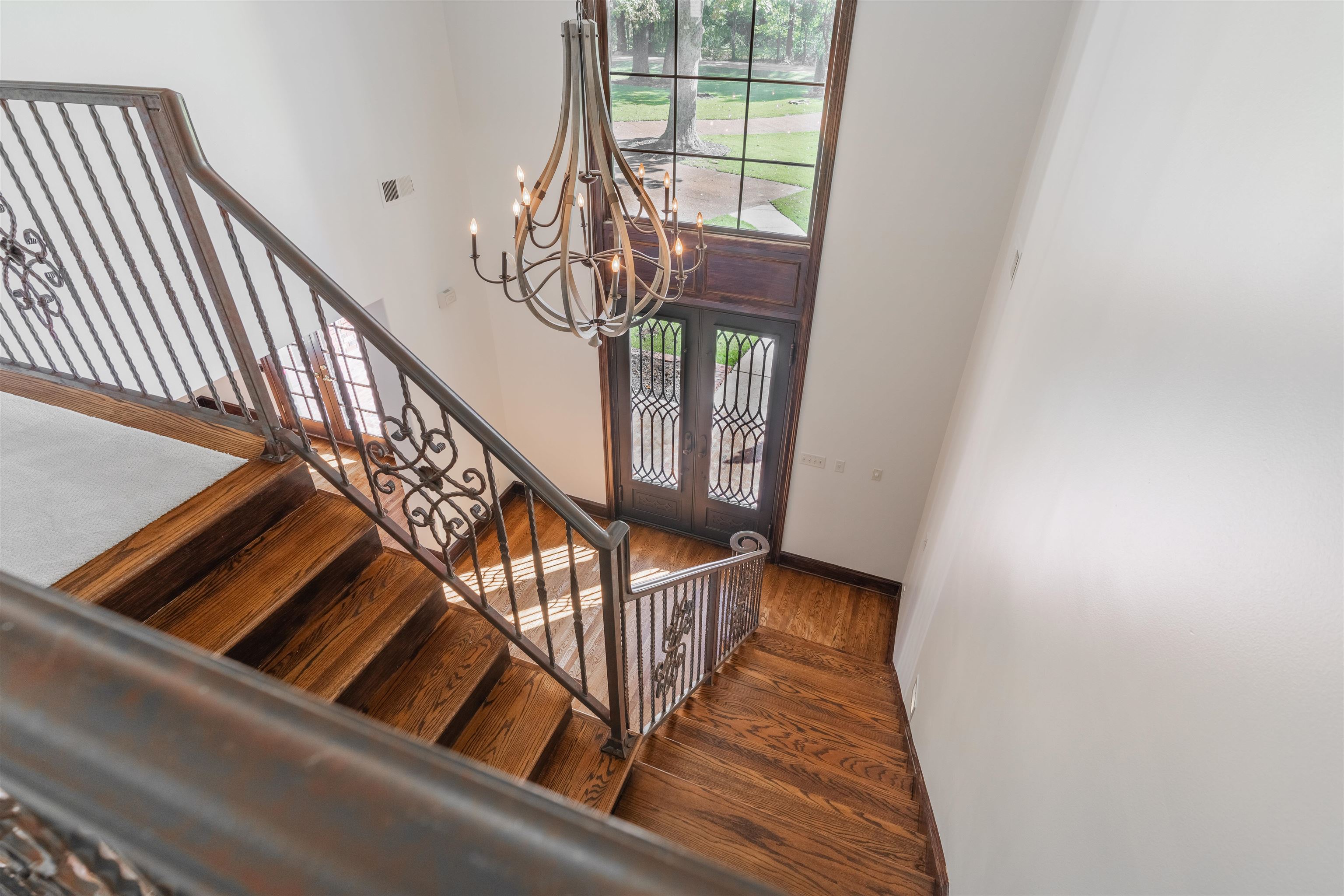 Stairway featuring hardwood / wood-style flooring, a notable chandelier, and french doors