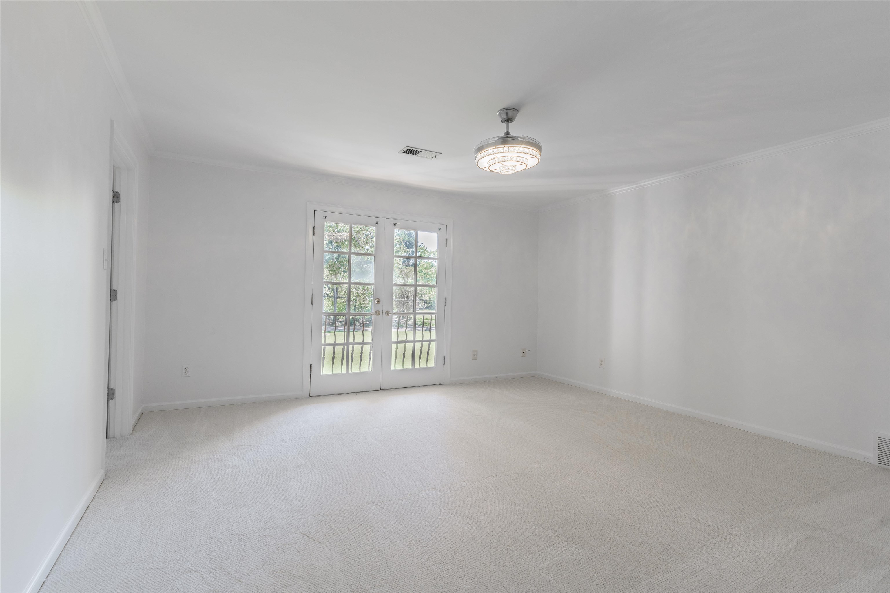 Carpeted spare room featuring french doors and ornamental molding