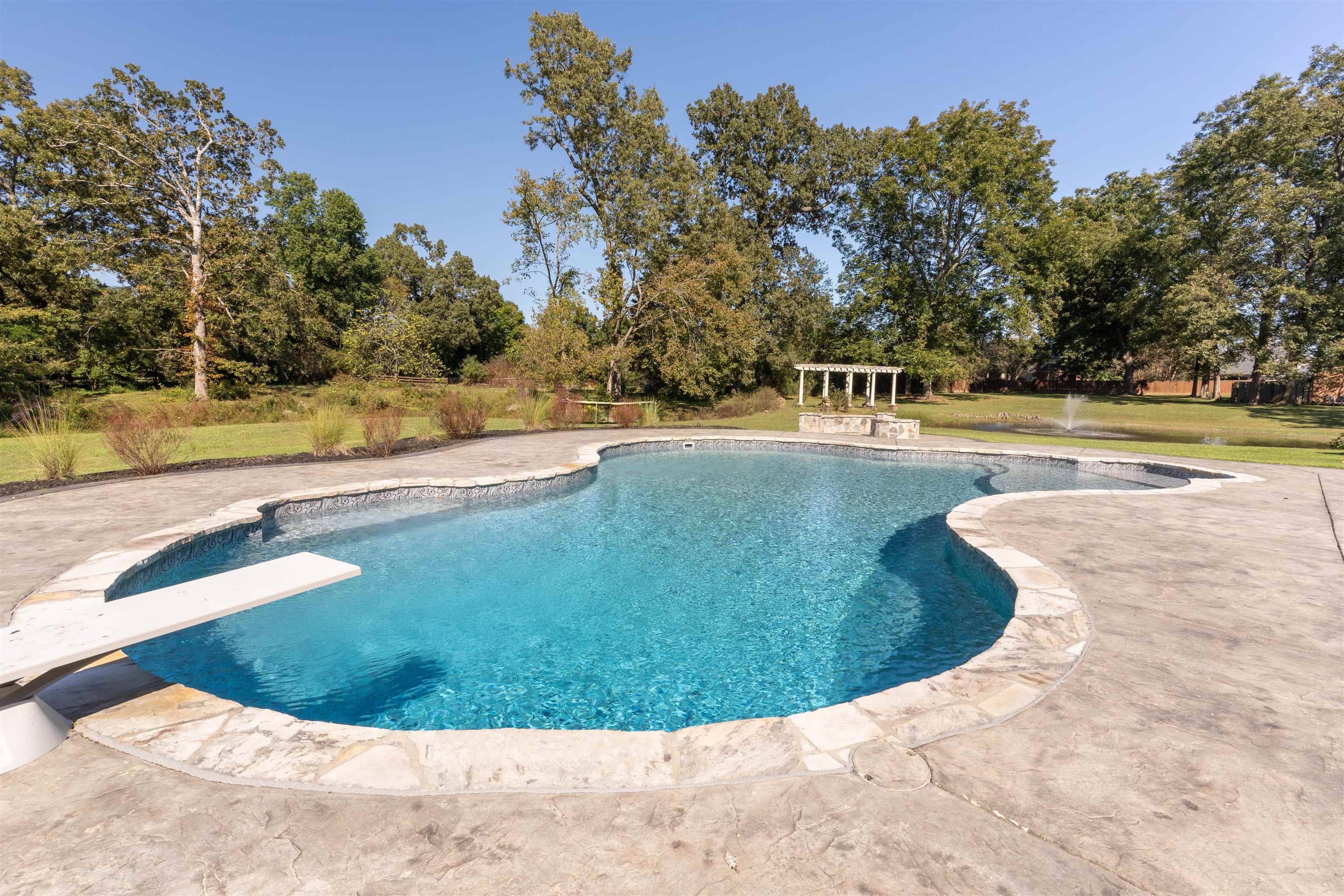 View of pool with a diving board, a lawn, and a patio