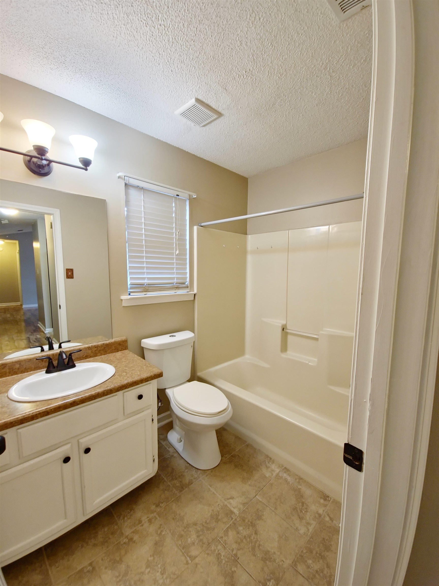 Full bathroom with shower / bath combination, vanity, toilet, and a textured ceiling