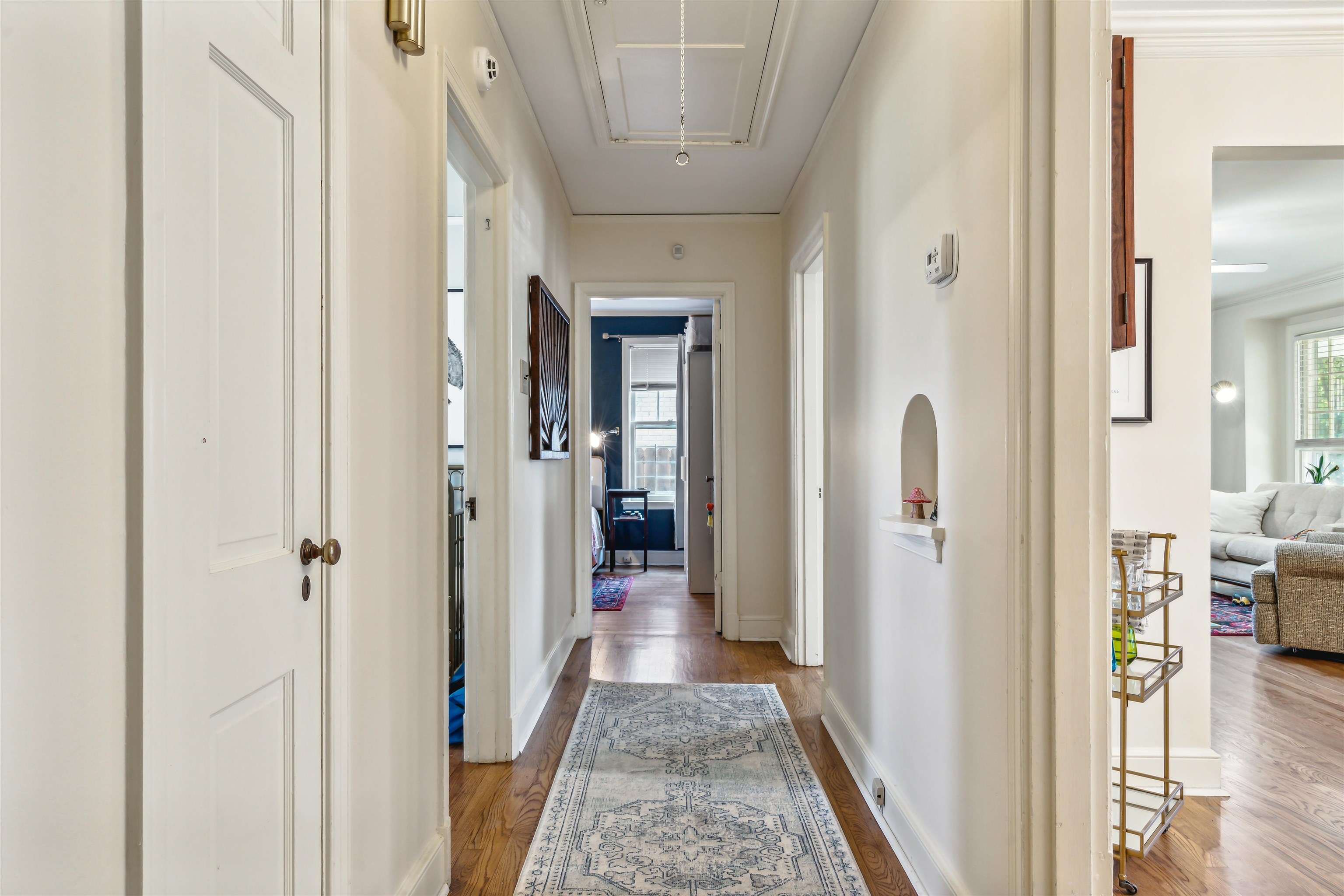 Corridor with ornamental molding and light hardwood / wood-style floors