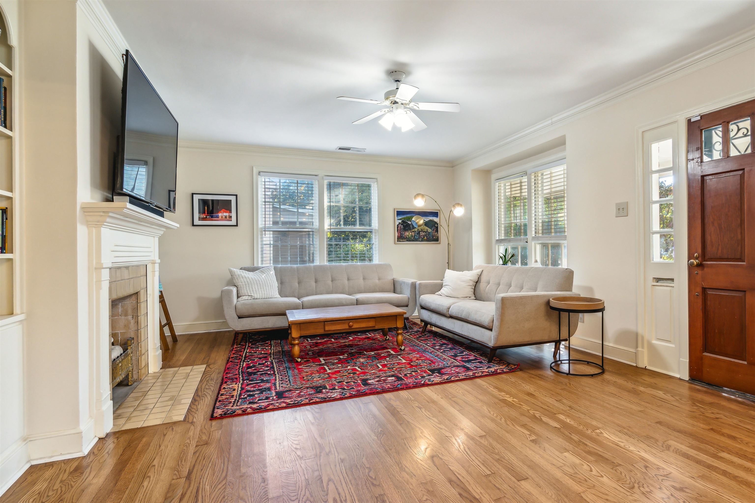 Living room with ornamental molding, a tiled fireplace, plenty of natural light, and light hardwood / wood-style flooring