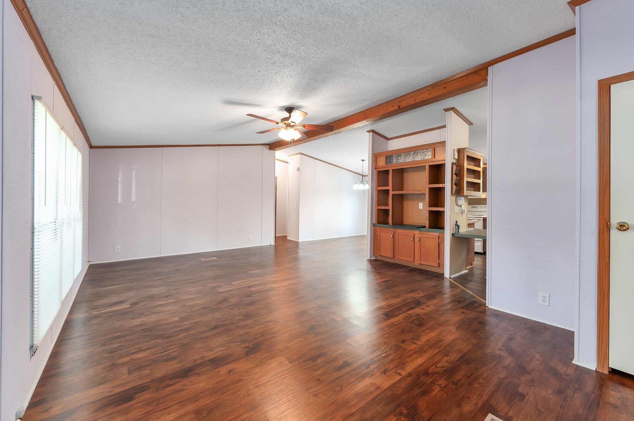 Unfurnished living room with ceiling fan, dark hardwood / wood-style flooring, and a textured ceiling