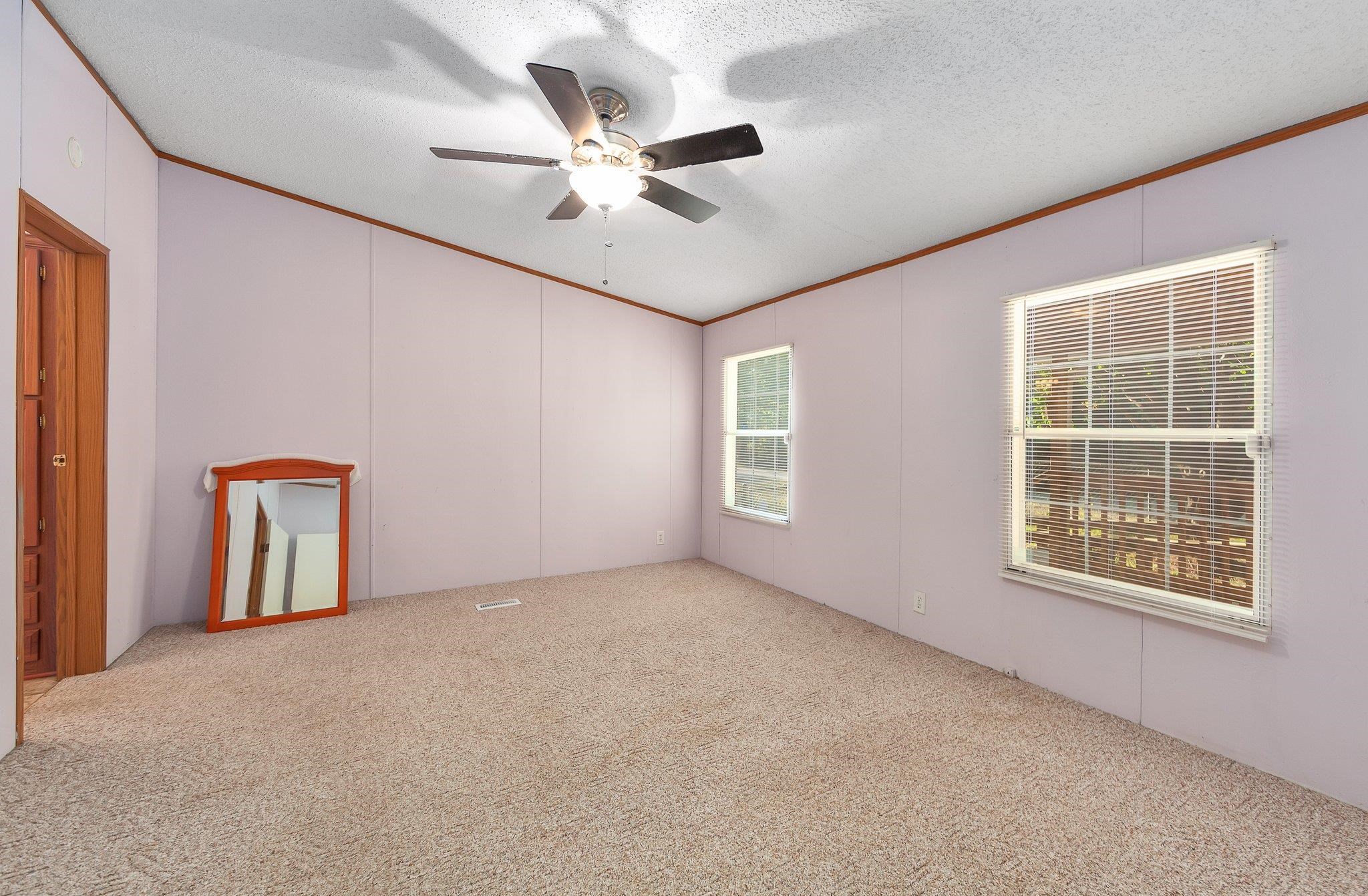 Empty room with light colored carpet, ceiling fan, and a textured ceiling