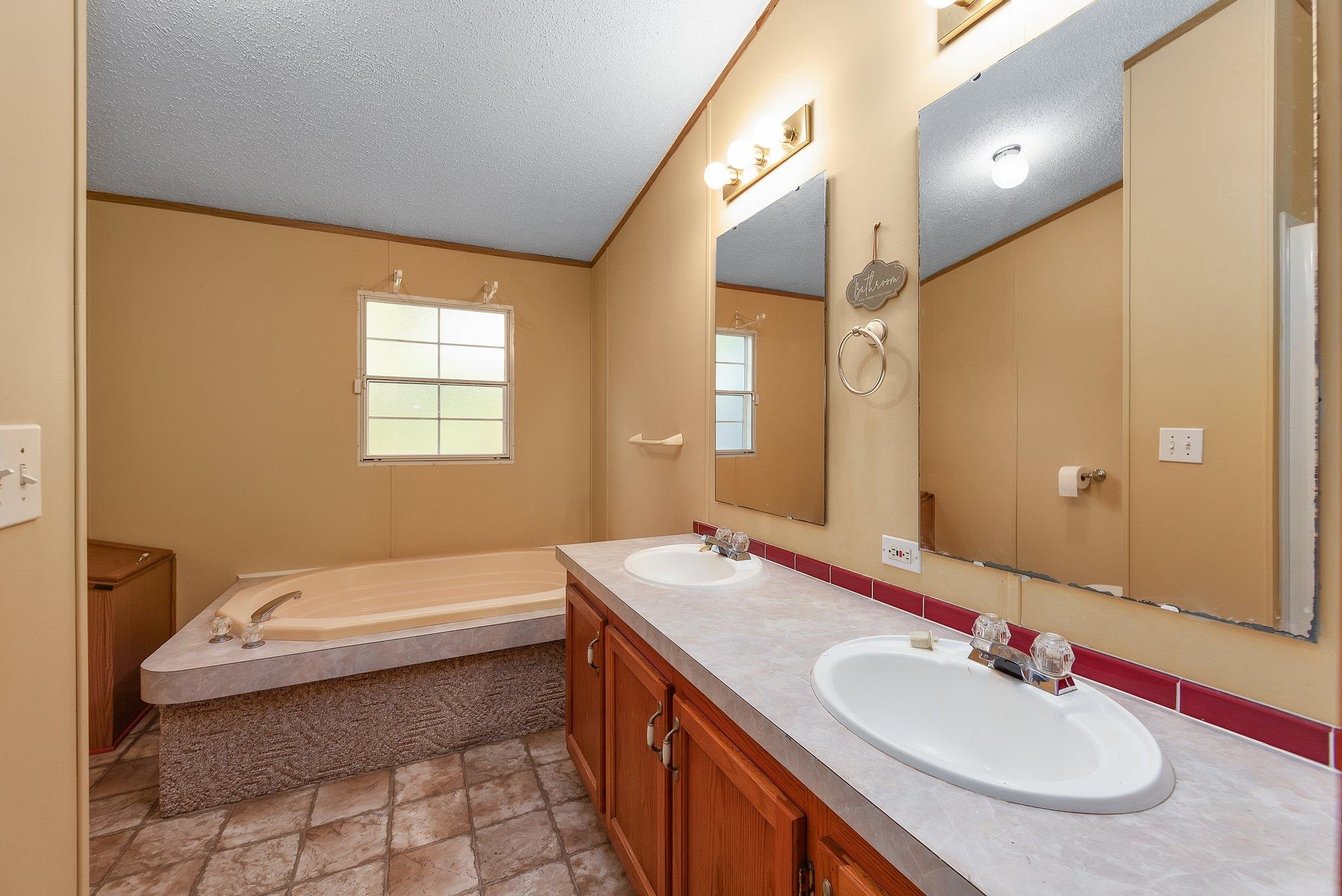 Bathroom with a washtub, vanity, and a textured ceiling