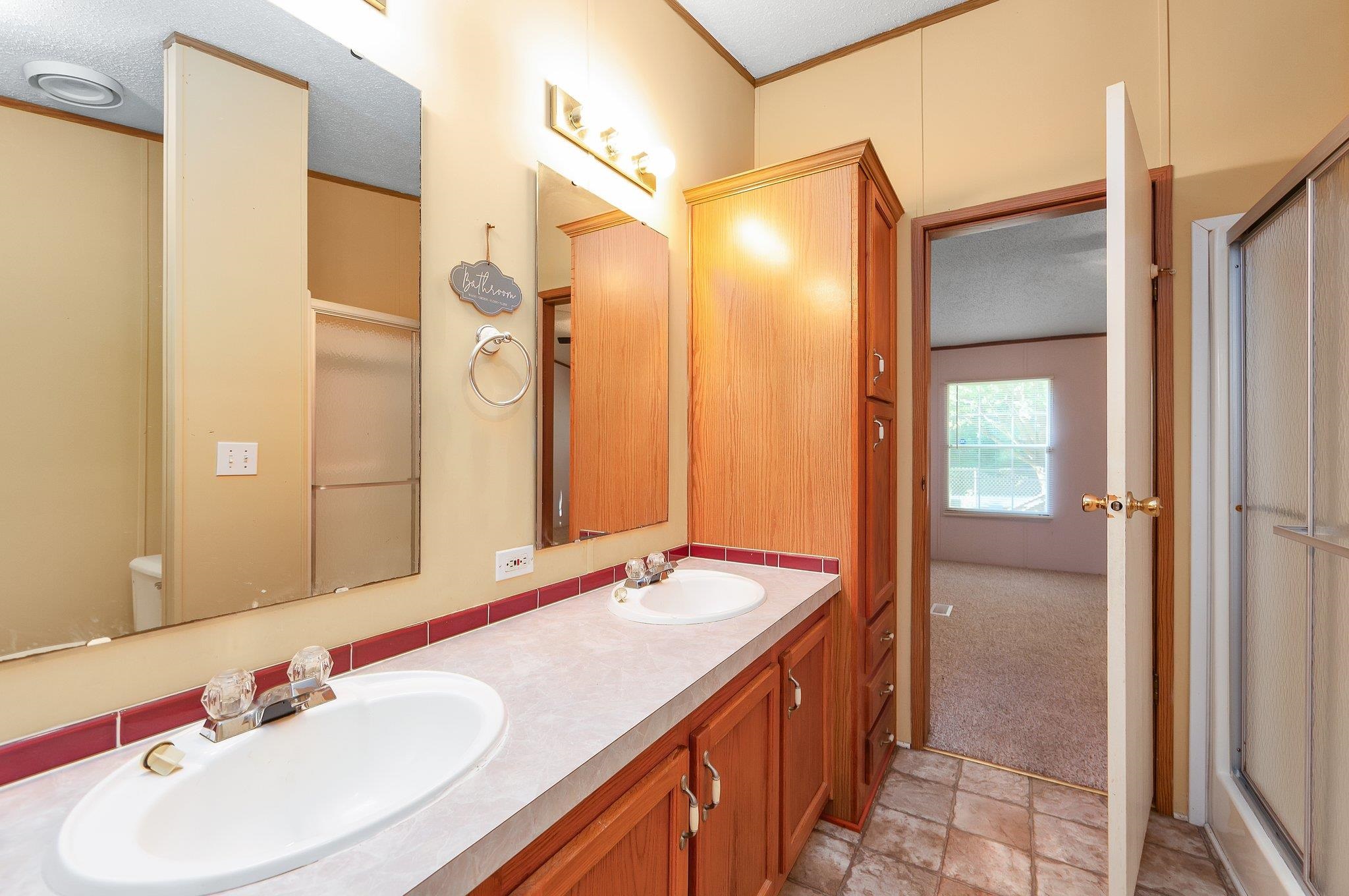 Bathroom with an enclosed shower, vanity, and a textured ceiling