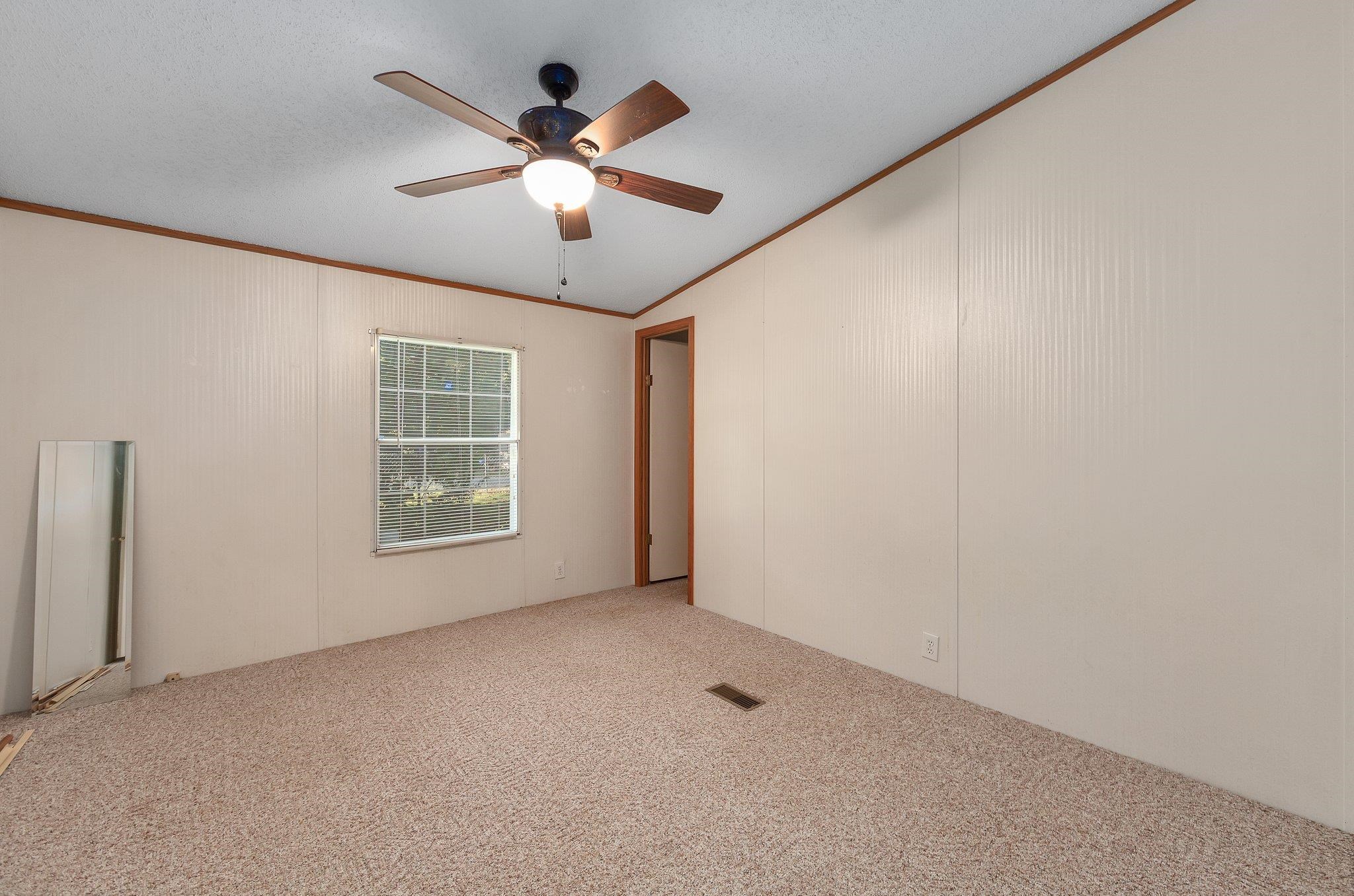 Spare room featuring ceiling fan, a textured ceiling, carpet floors, crown molding, and vaulted ceiling