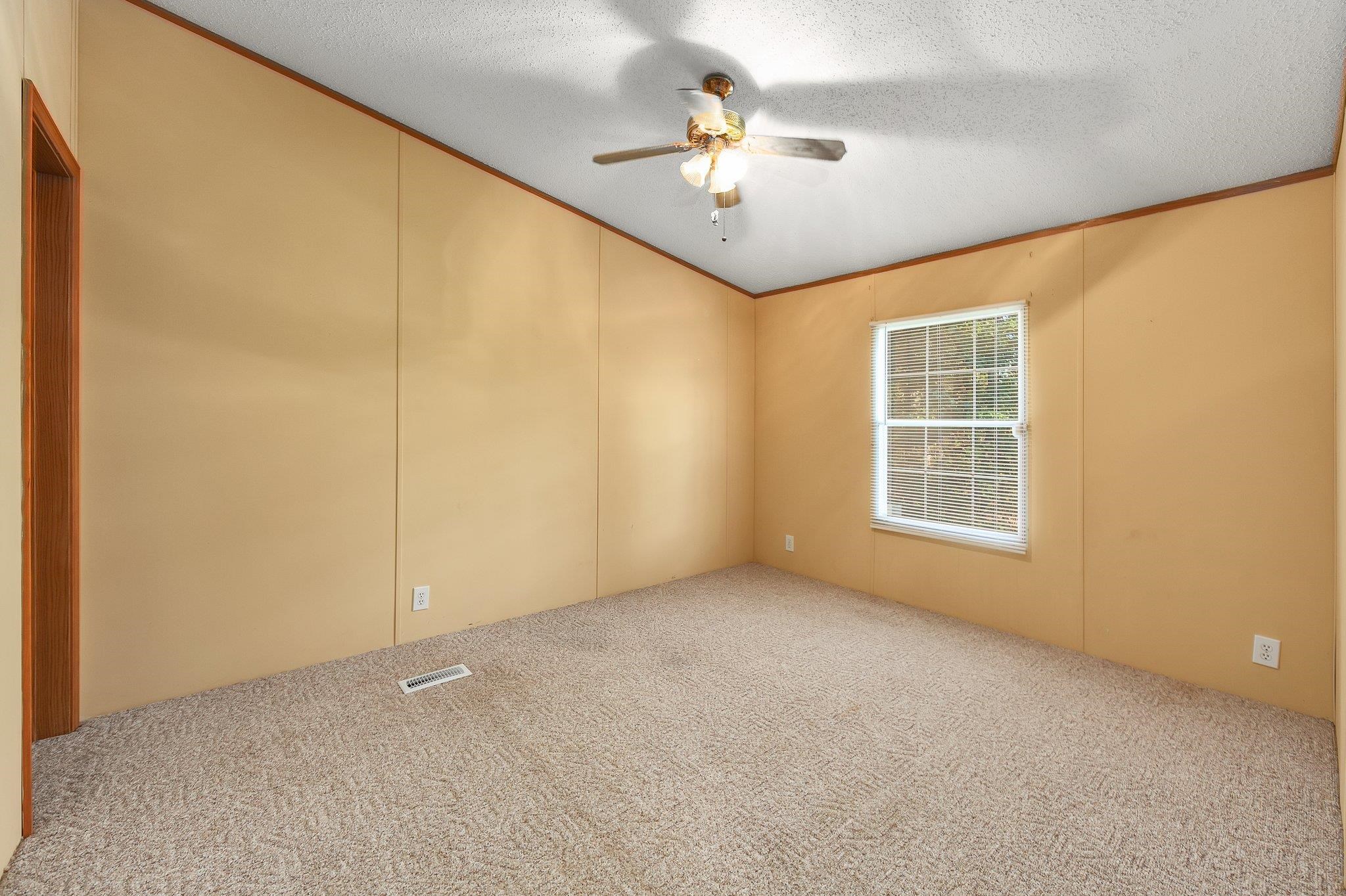 Empty room with ceiling fan, carpet, and a textured ceiling