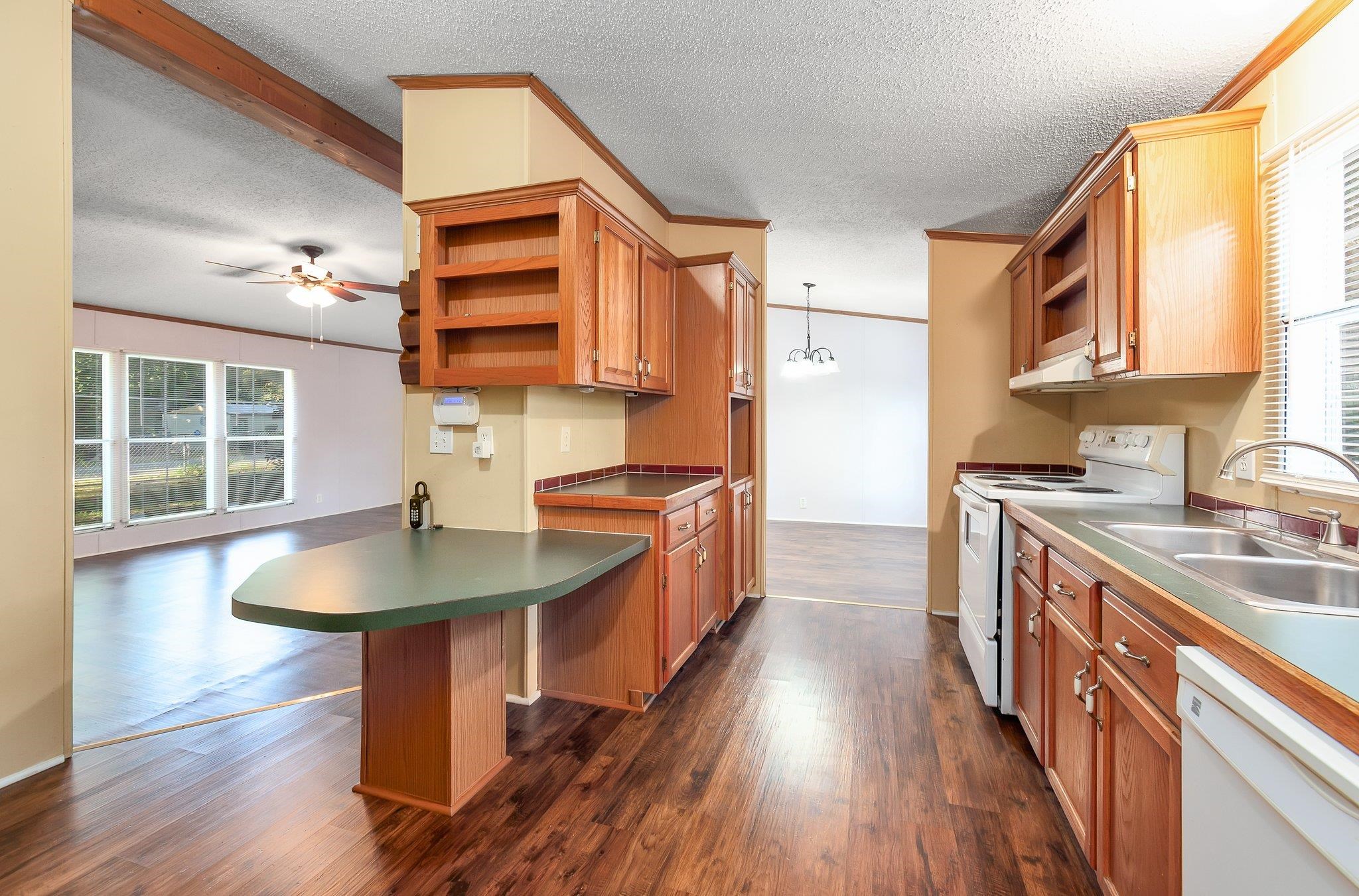 Kitchen featuring dark hardwood / wood-style floors, a breakfast bar, white appliances, sink, and decorative light fixtures